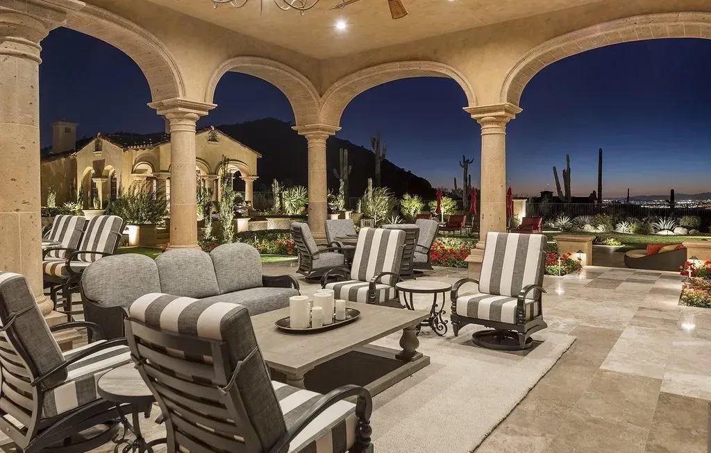 Outdoor patio at dusk with seating, arches, and a view of mountains.