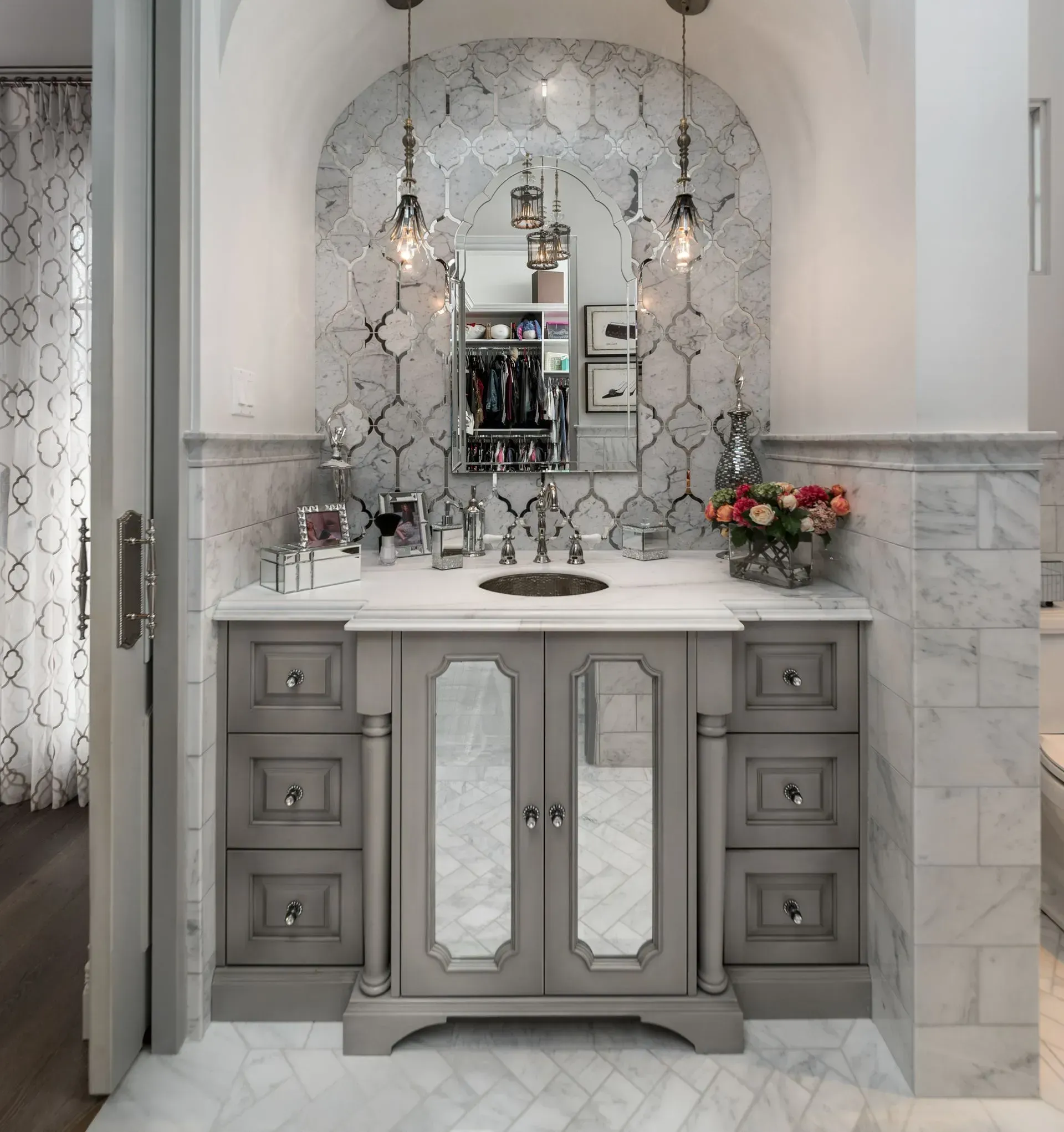 Bathroom vanity with gray cabinet, marble countertop, and patterned backsplash.