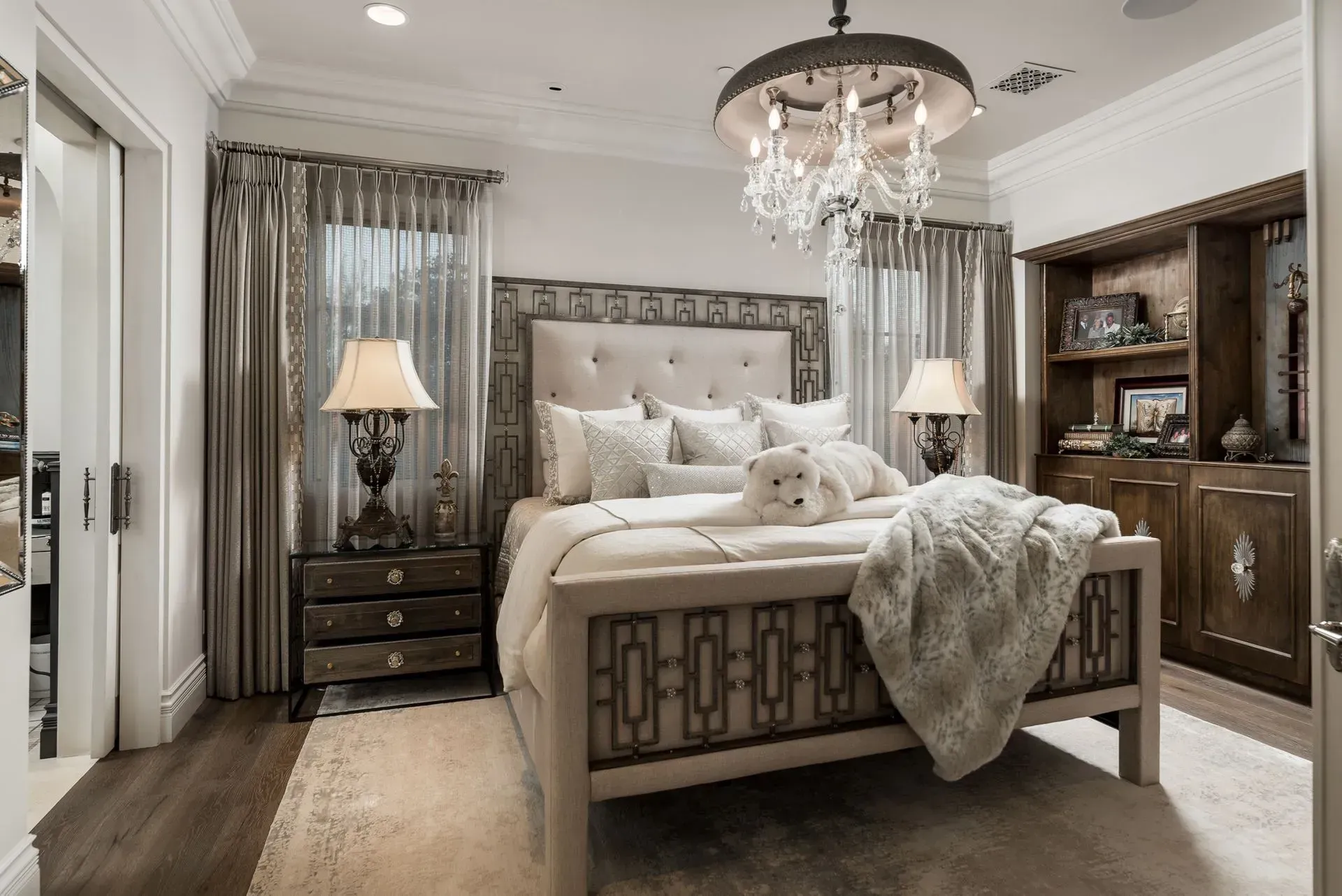 Elegant bedroom with a tufted headboard, mirrored nightstands, and a crystal chandelier.