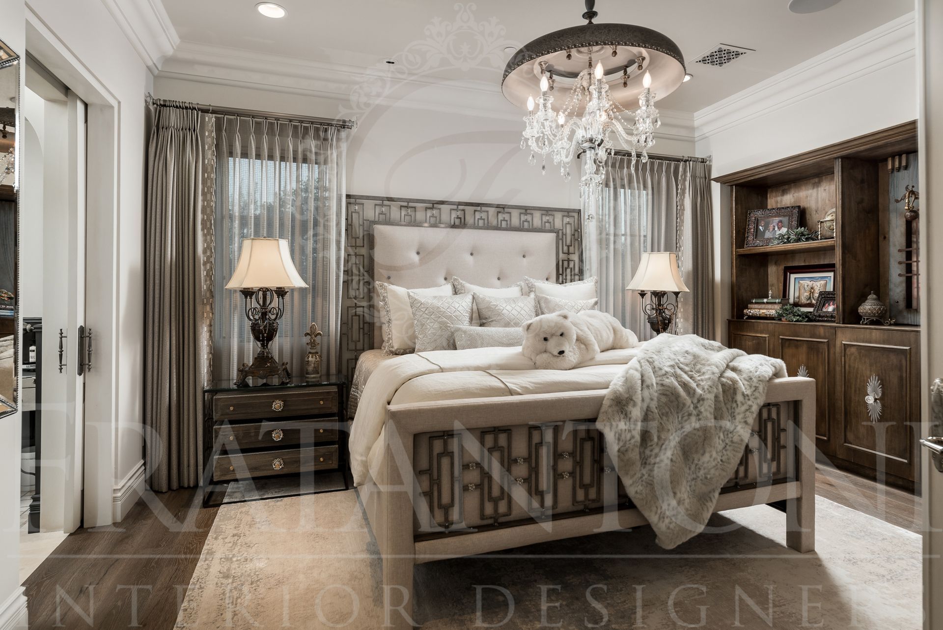 Elegant bedroom with upholstered bed, nightstands, crystal chandelier, and built-in shelves.