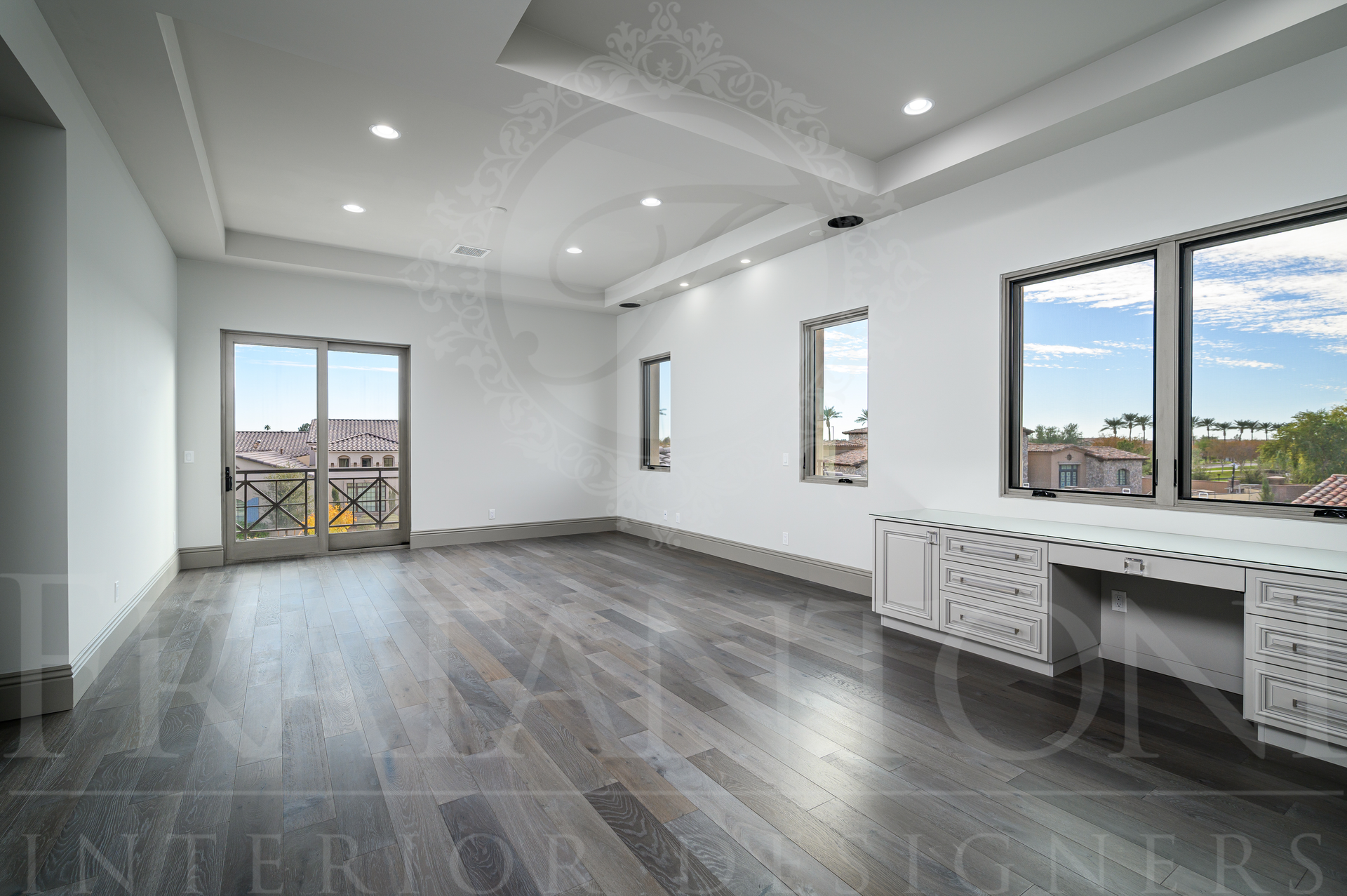 Bright elegant bedroom with gray floors, white walls, large windows, balcony doors, and a built in vanity.