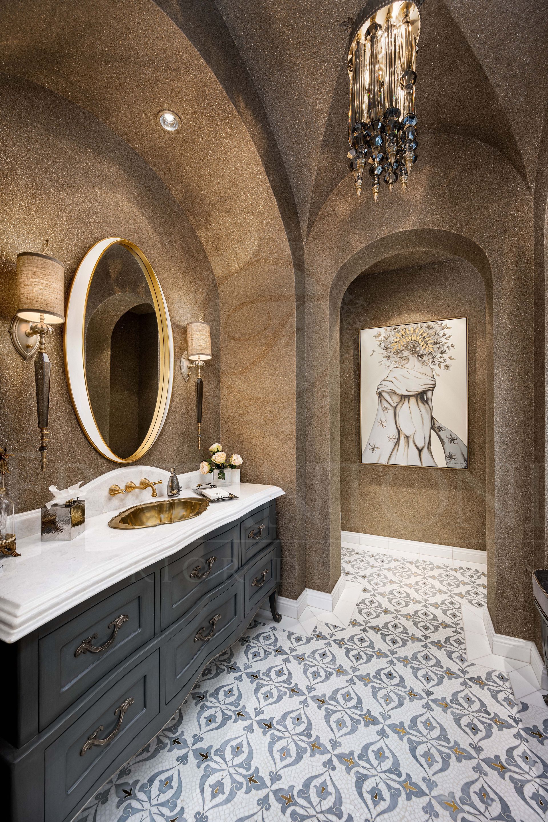Elegant bathroom with textured brown walls, arched doors, a vaulted ceiling, round mirror, wall sconces, dark custom vanity, and patterned mosaic tile floor.