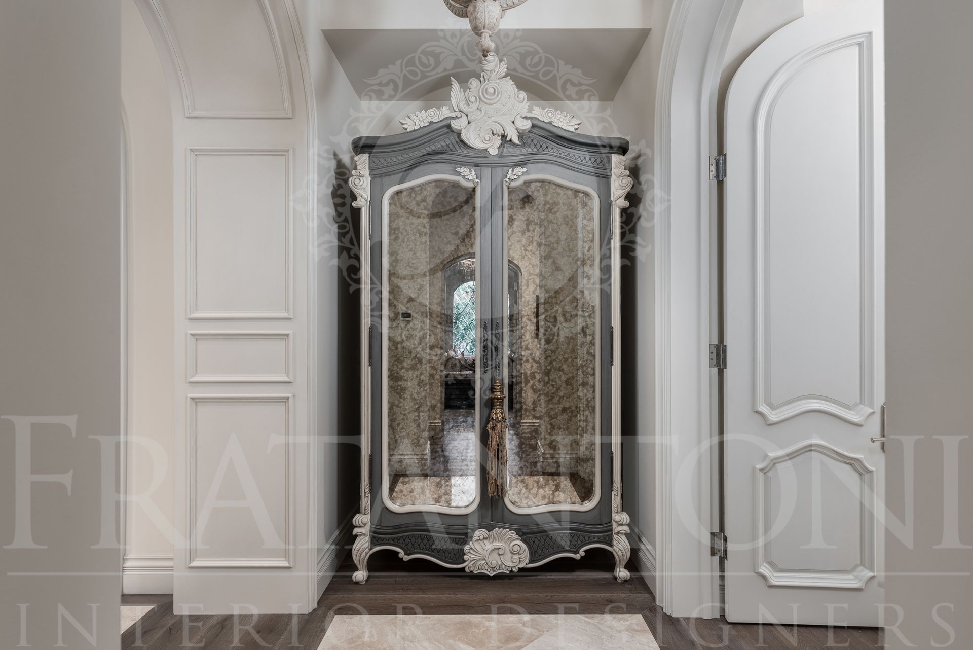 Elaborate ornate grey and white mirrored cabinet in a hallway.