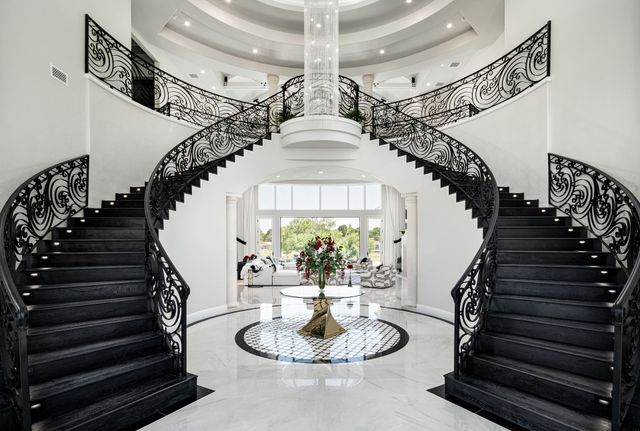 Modern dual staircase interior design, high contrast with chandelier and marble flooring.