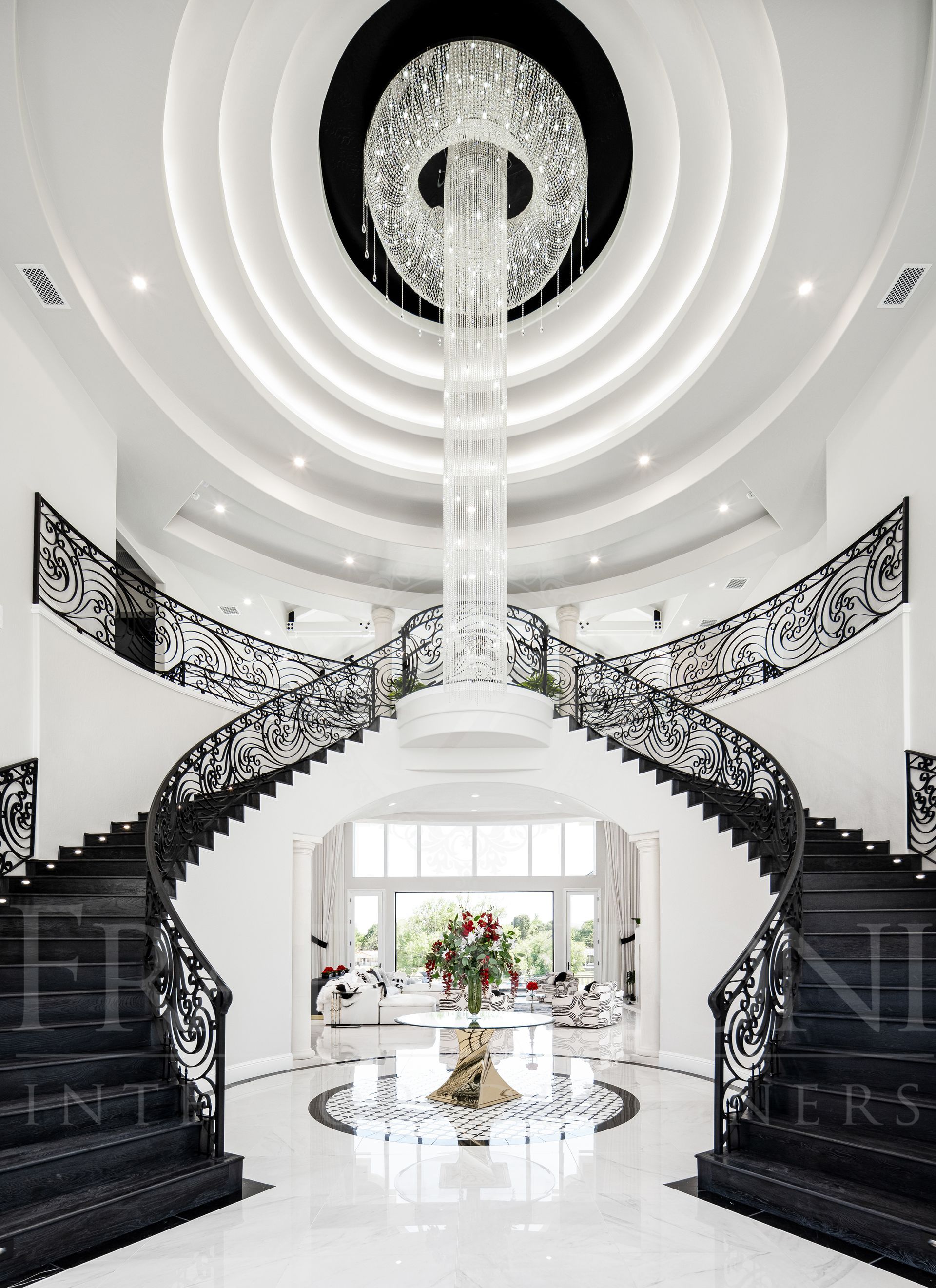 Grand, white foyer with a black spiral staircase, chandelier, and a floral centerpiece designed by Fratantoni Interior Designers in scottsdale arizona