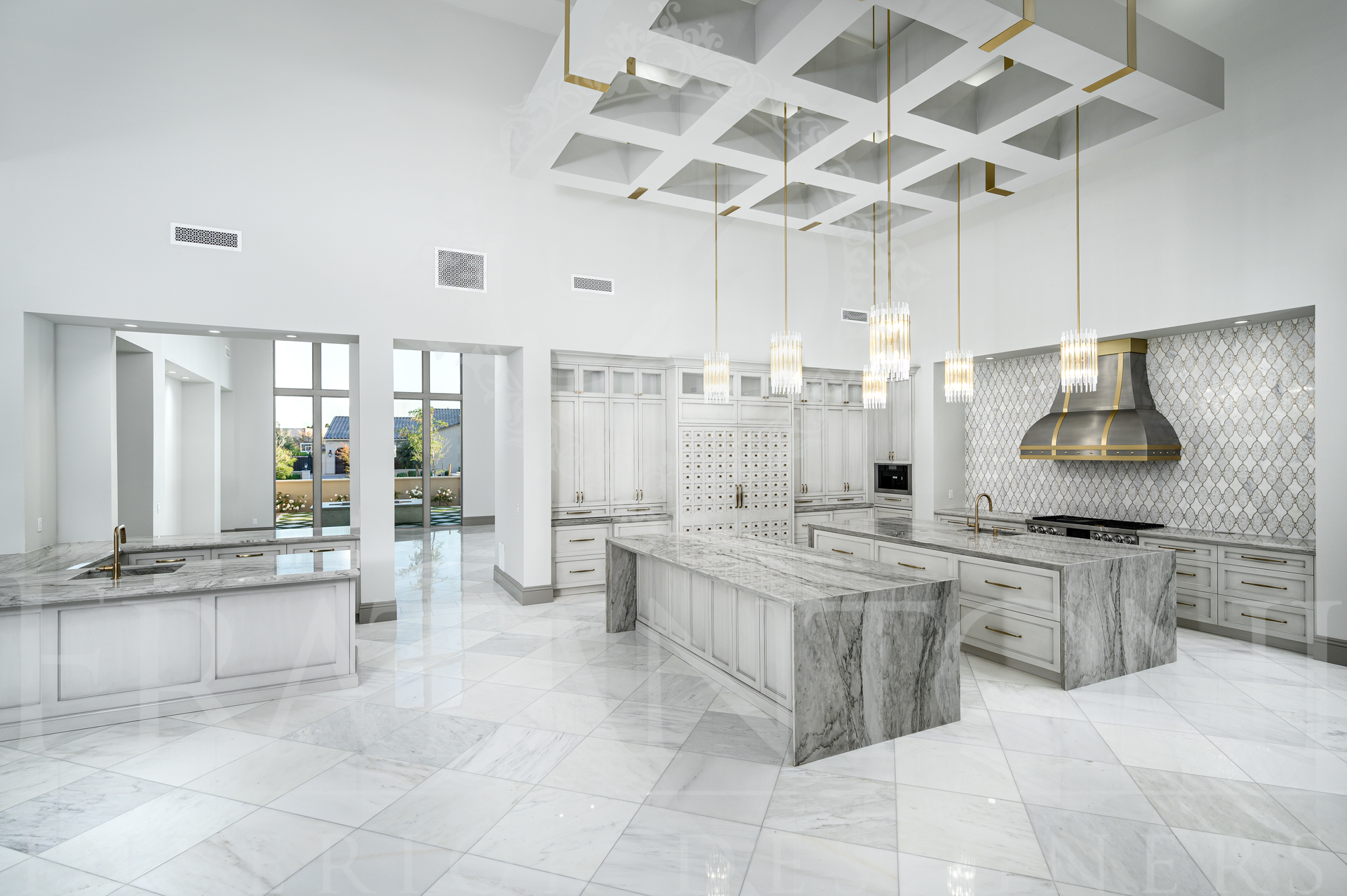 Bright white luxury kitchen with marble countertops, two islands, patterned backsplash, and geometric ceiling lights