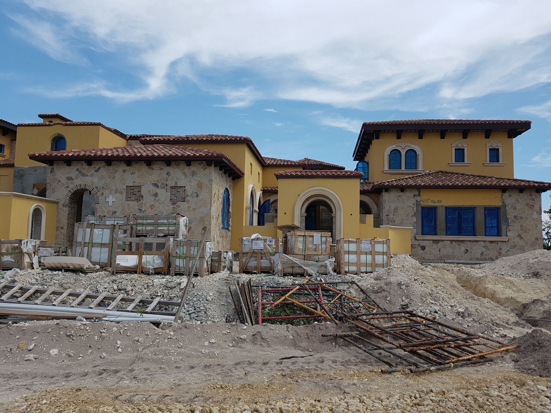 Yellow and stone house under construction with a blue sky.