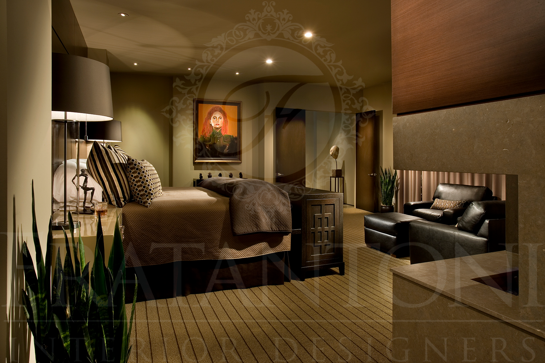 Luxurious master bedroom with a large bed, leather chairs, a fireplace, and warm, dark lighting.