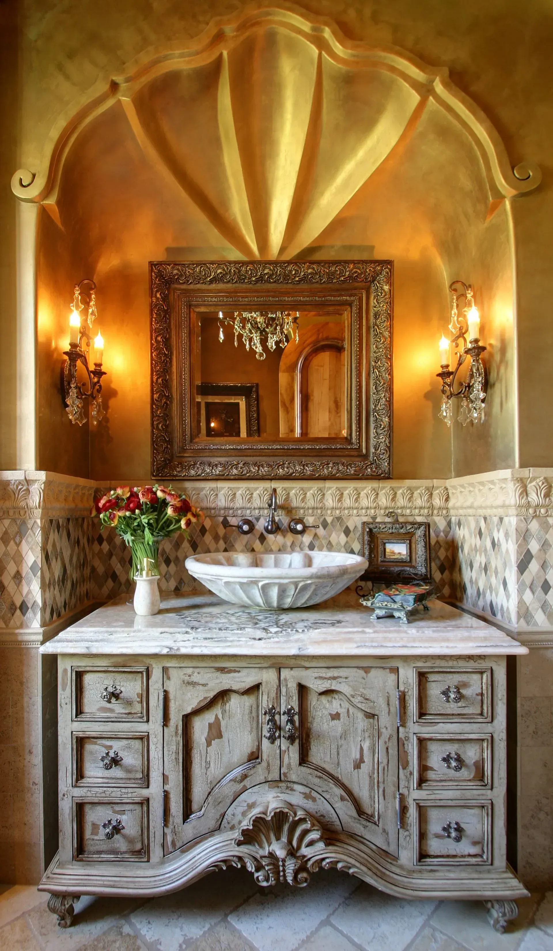 Ornate bathroom with gold accents, distressed wooden vanity, stone sink, and sconces.