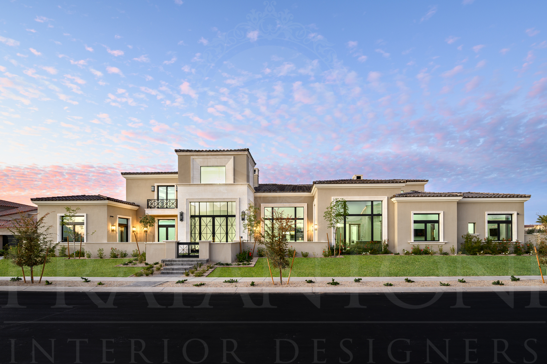 Luxury two-story house at dusk with warm interior lights, a central entrance, and desert landscaping in Scottsdale Arizona.