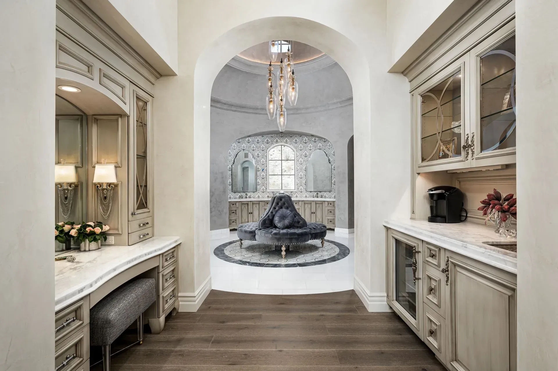 Vanity area with a dressing table and cabinets, leading to a circular lounge with a chandelier.