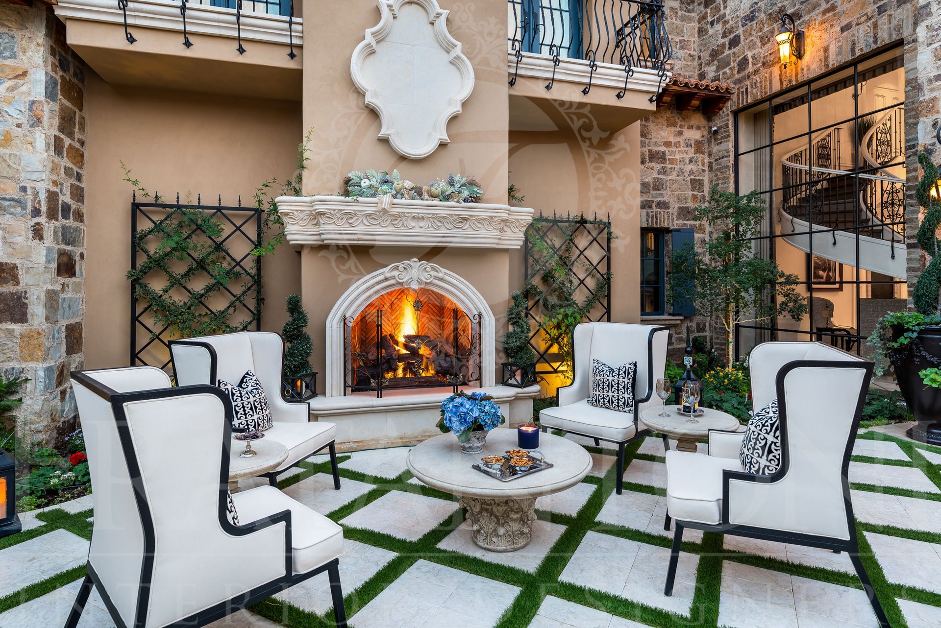 Luxurious outdoor seating area with fireplace, stone walls, and green grass pattern. White chairs, black trim, and floral accents in scottsdale arizona