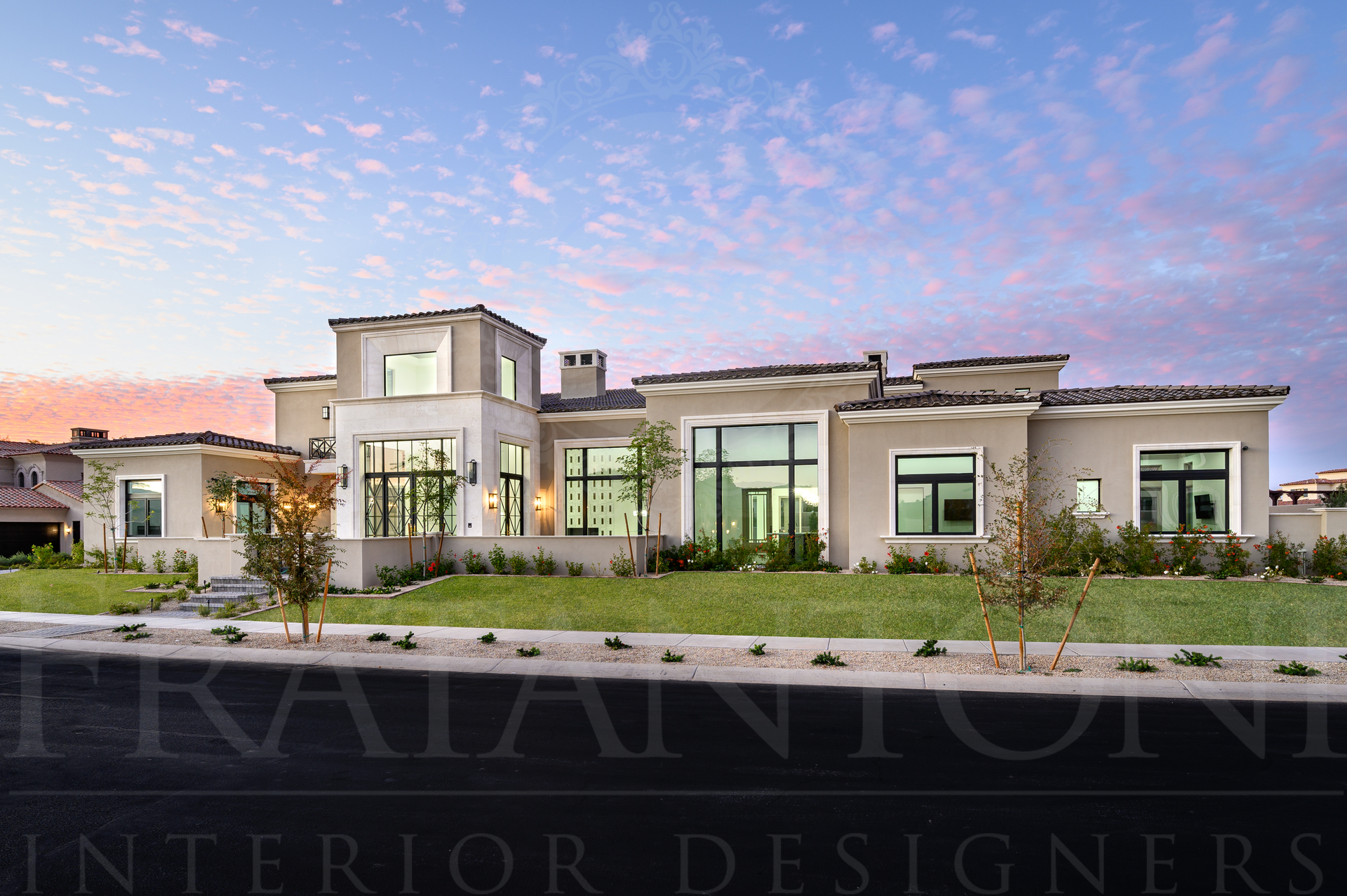 Modern luxury villa at sunset with beige walls, large windows, and landscaped desert greenery in arizona