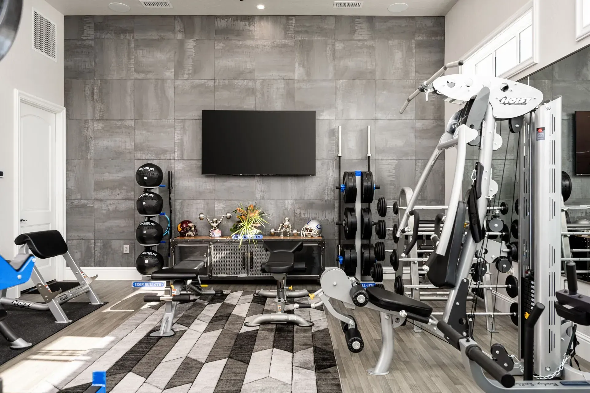 Home gym with weight machines, free weights, TV, and decorative items.