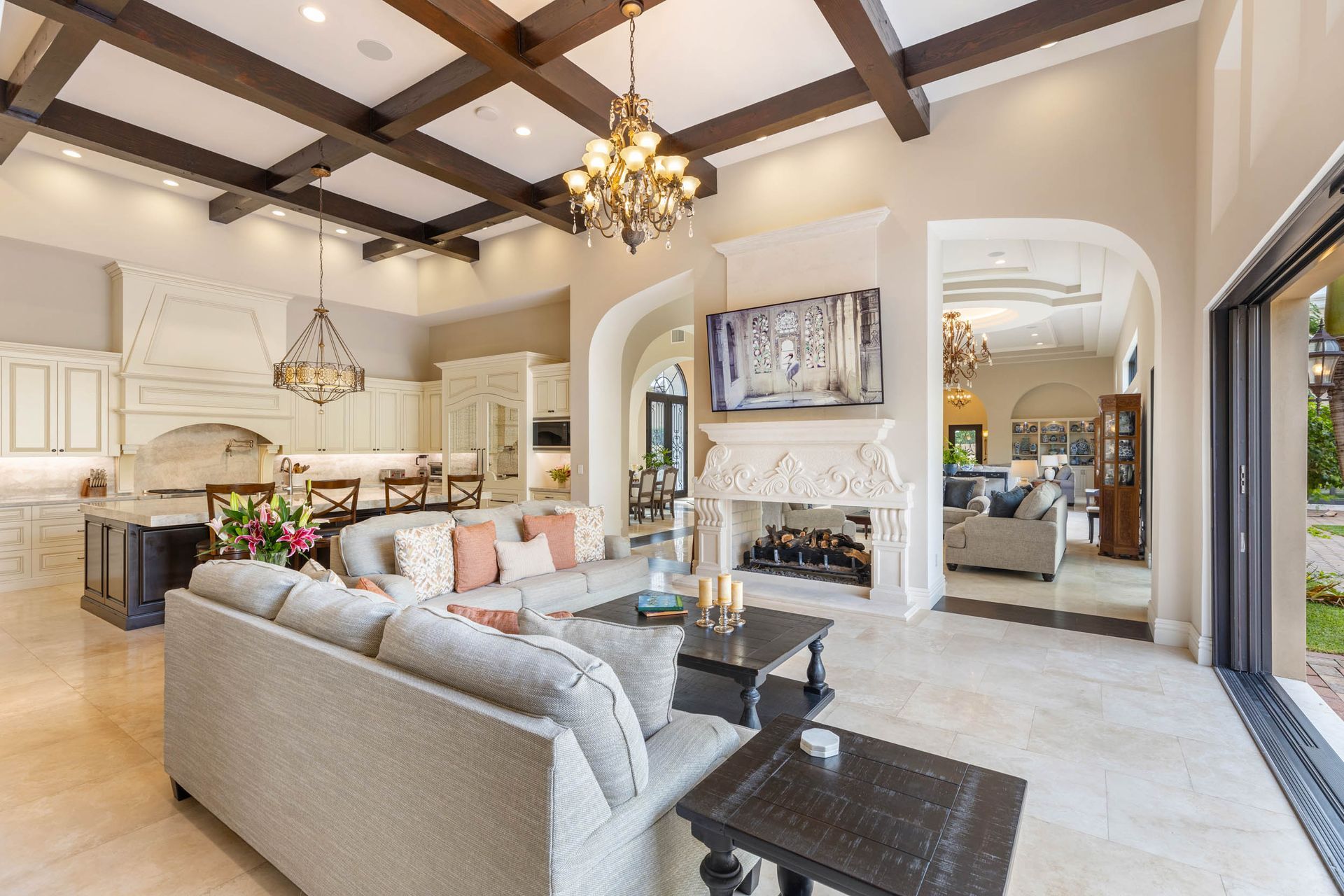 Spacious living room with a kitchen, fireplace, and arched doorways, beige and brown tones.