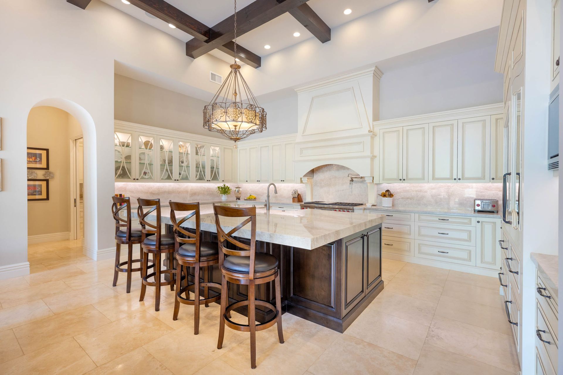 Spacious kitchen with a large island, cream cabinets, and a chandelier. The floor is light-colored tile.