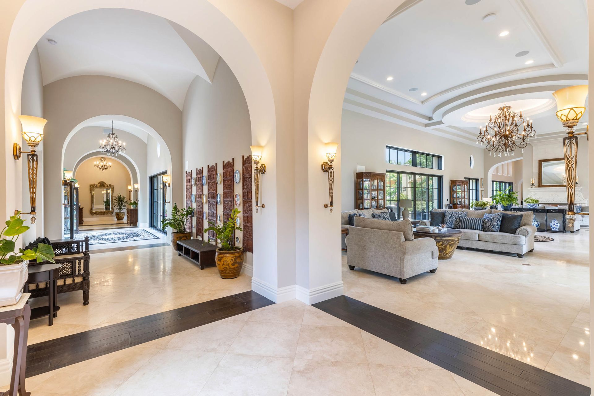 Elegant home interior with arched doorways, marble floors, and chandelier.