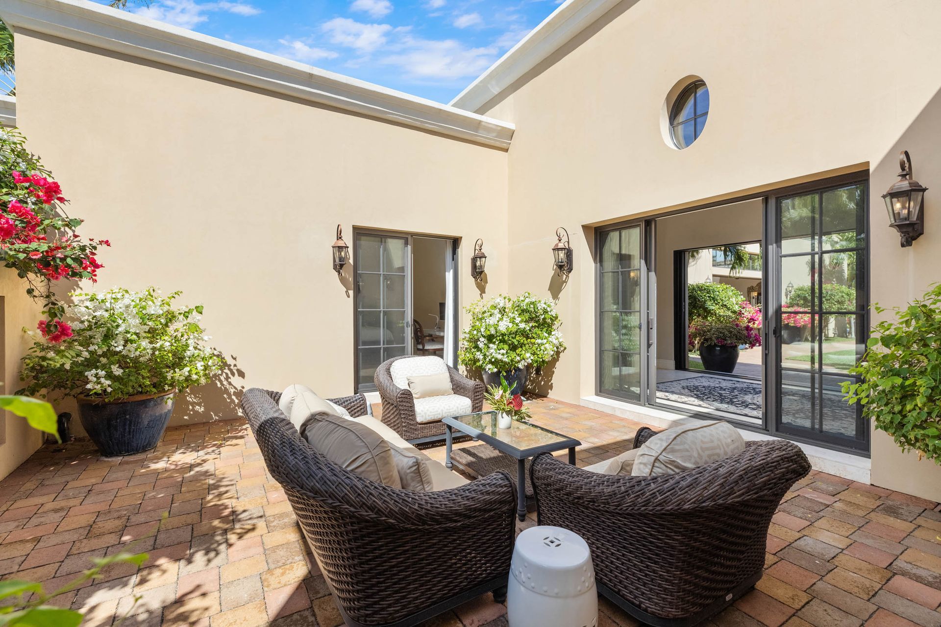 Outdoor patio with wicker furniture, brick floor, and tan walls; sliding glass door.