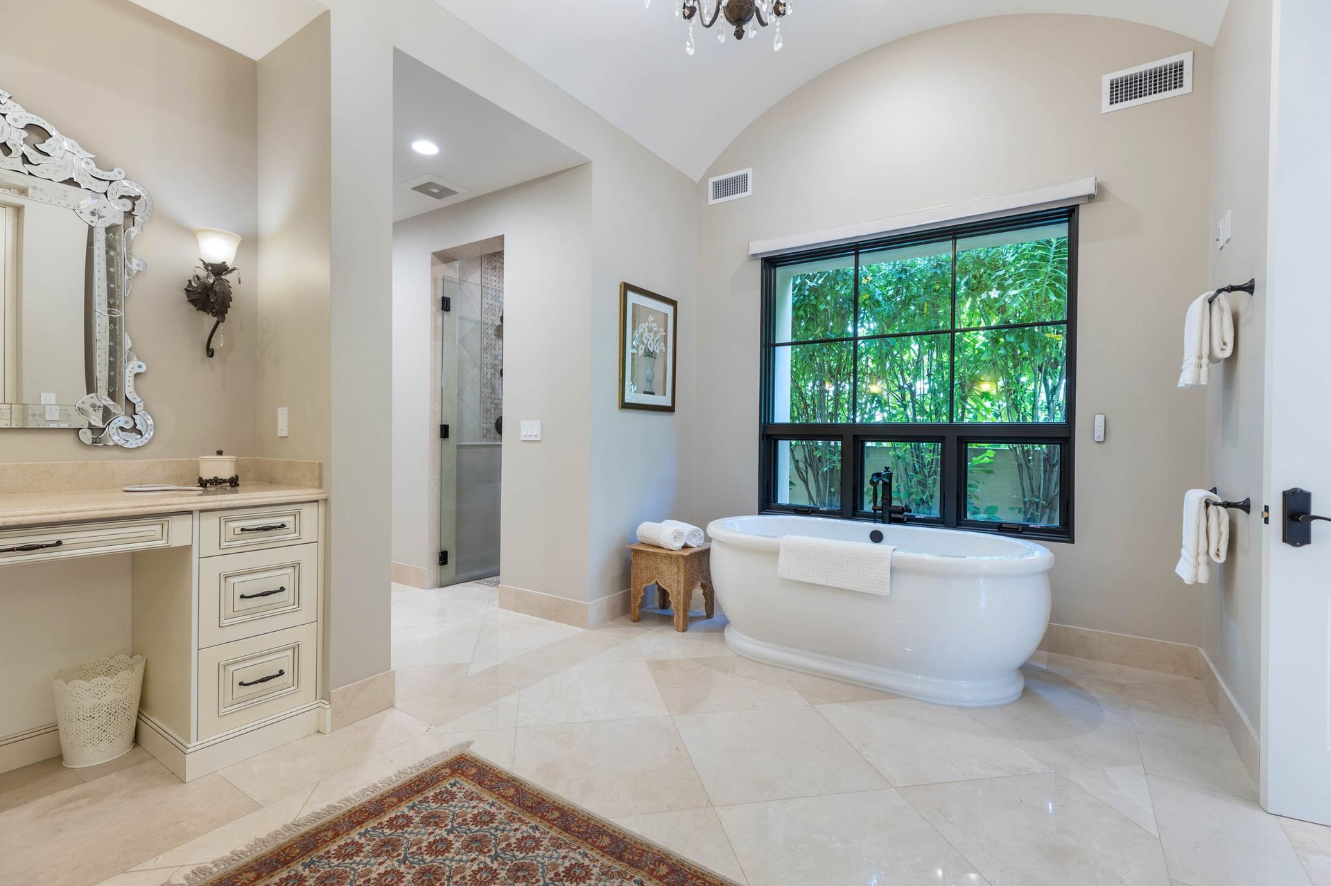 Luxurious bathroom with soaking tub, vanity, and window overlooking trees.