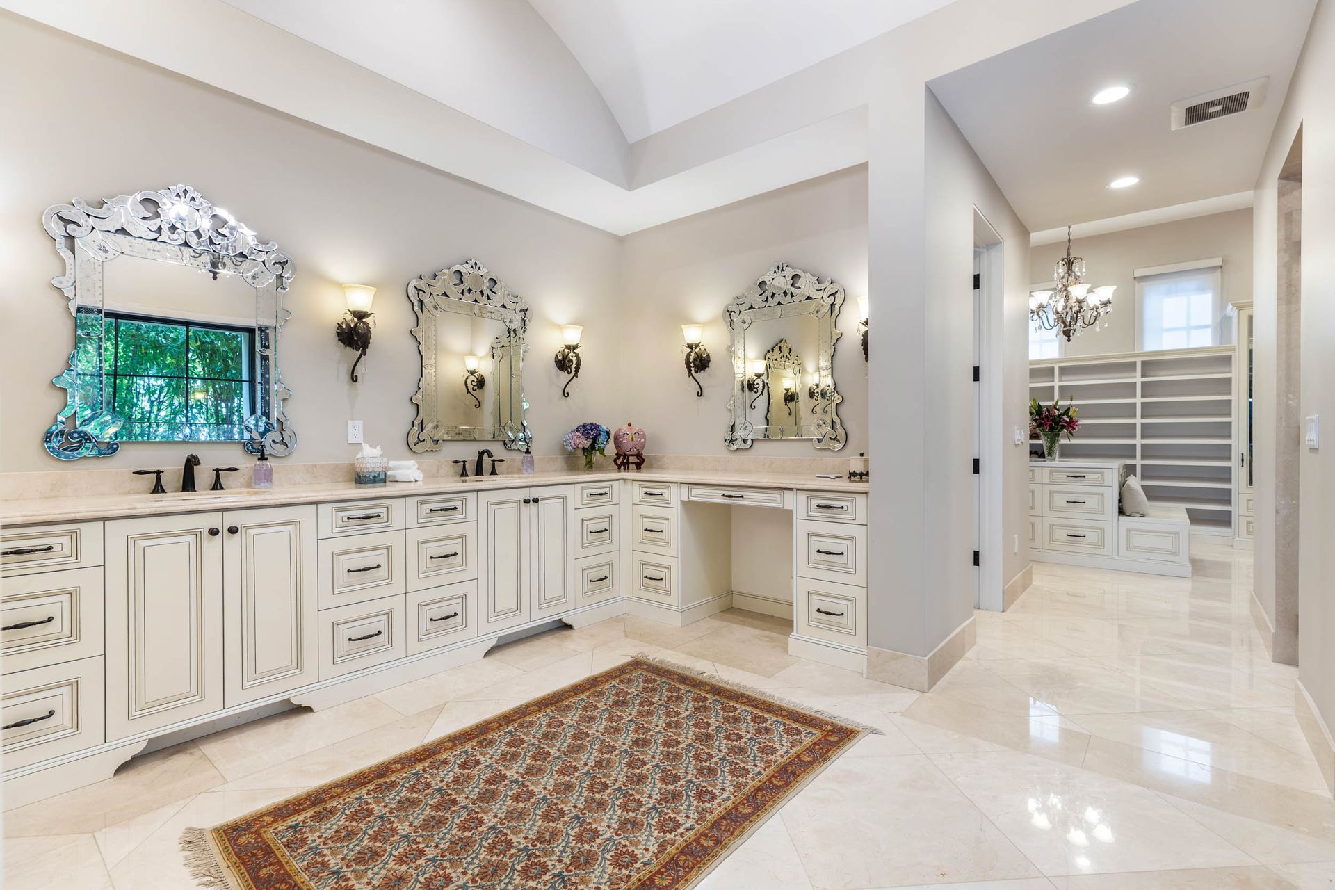 Bathroom with dual vanity, ornate mirrors, rug, and walk-in closet.