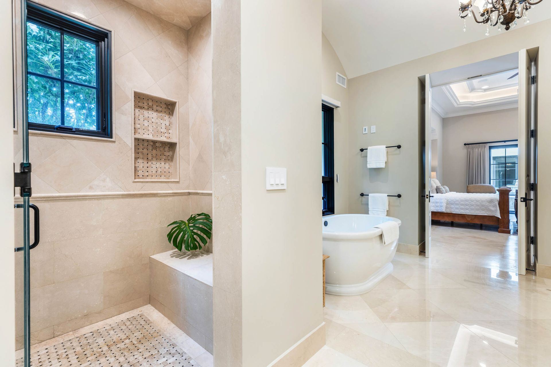 Elegant bathroom with shower, tub, and doorway to bedroom; neutral colors.