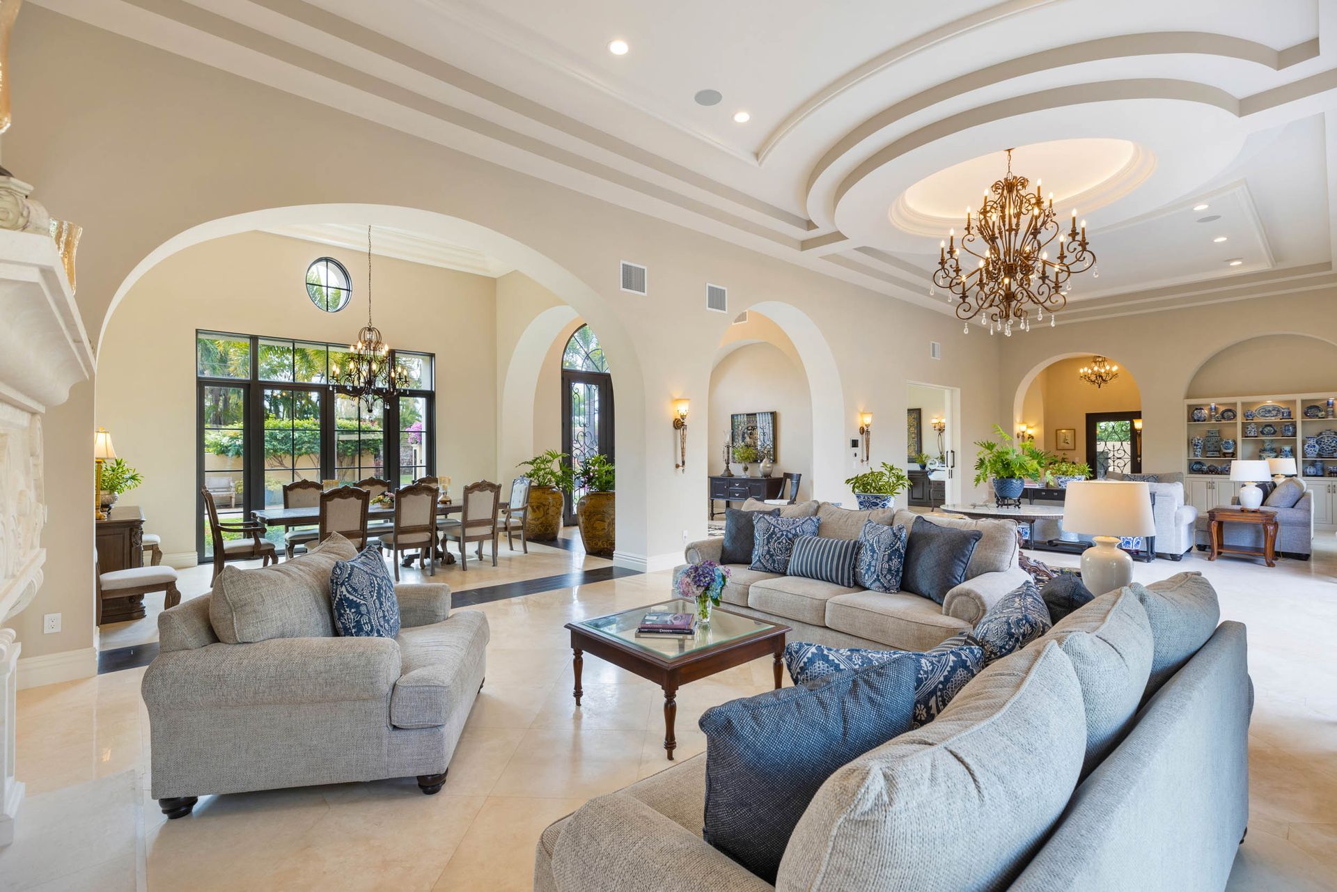 Spacious living room with arched doorways, ornate ceiling, large couches, and a chandelier.