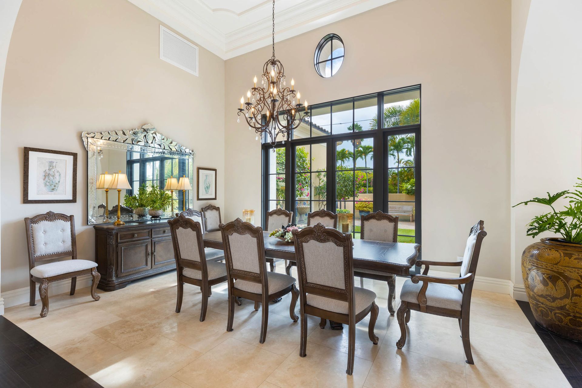 Formal dining room with dark wood table and chairs, chandelier, and a large window.
