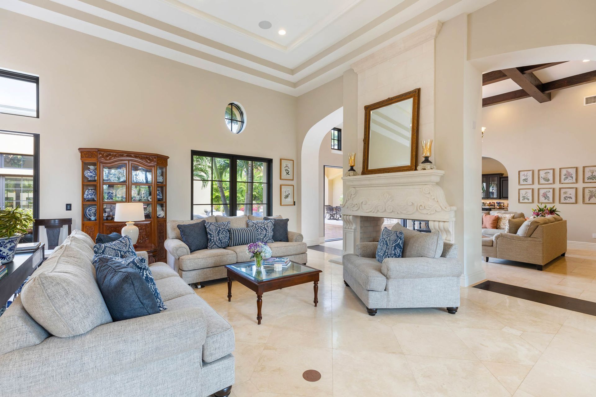 Spacious luxury living room with sofas, fireplace, and arched doorways; neutral color palette, natural light.