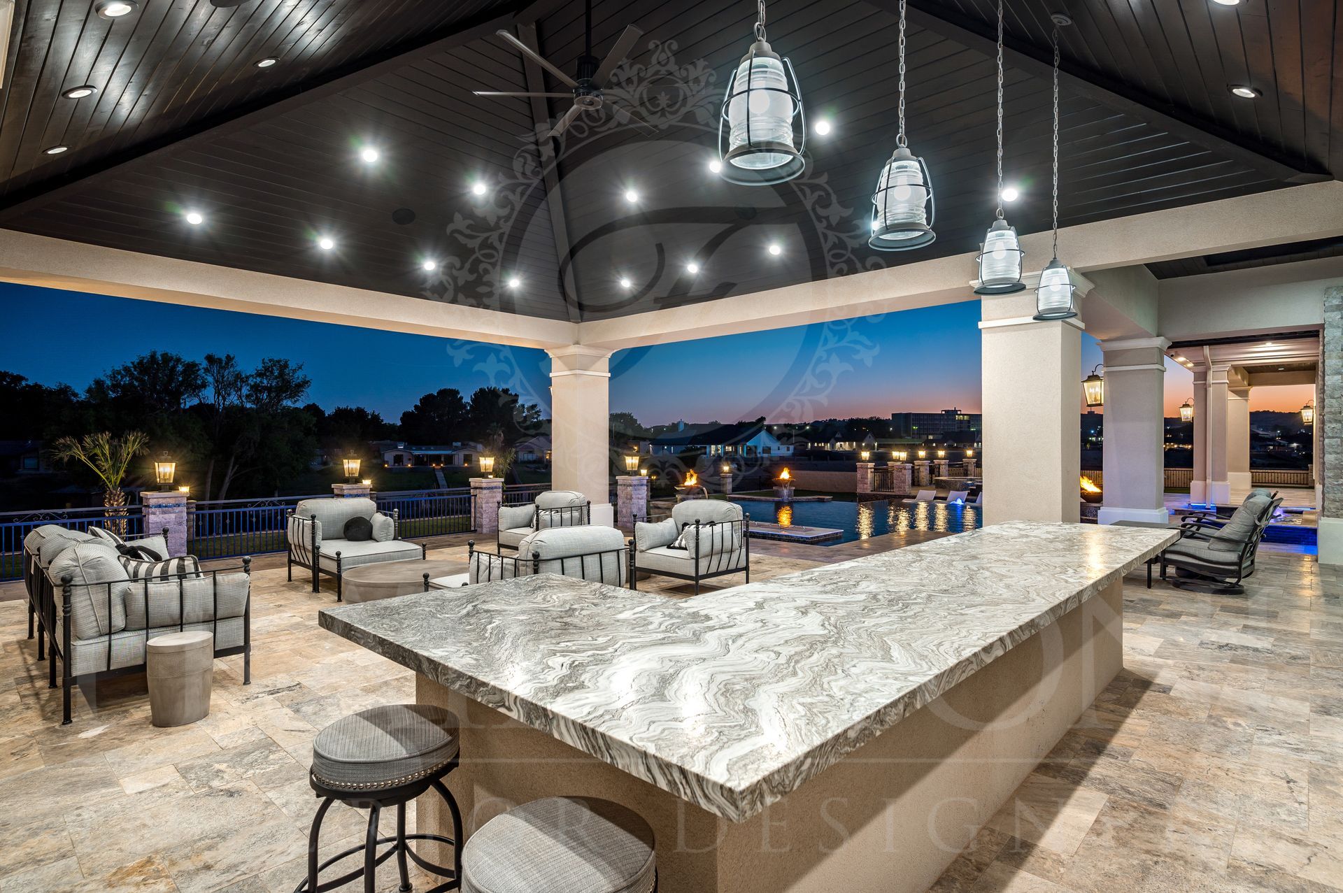 Outdoor patio with bar and seating overlooking resort style pool at dusk.