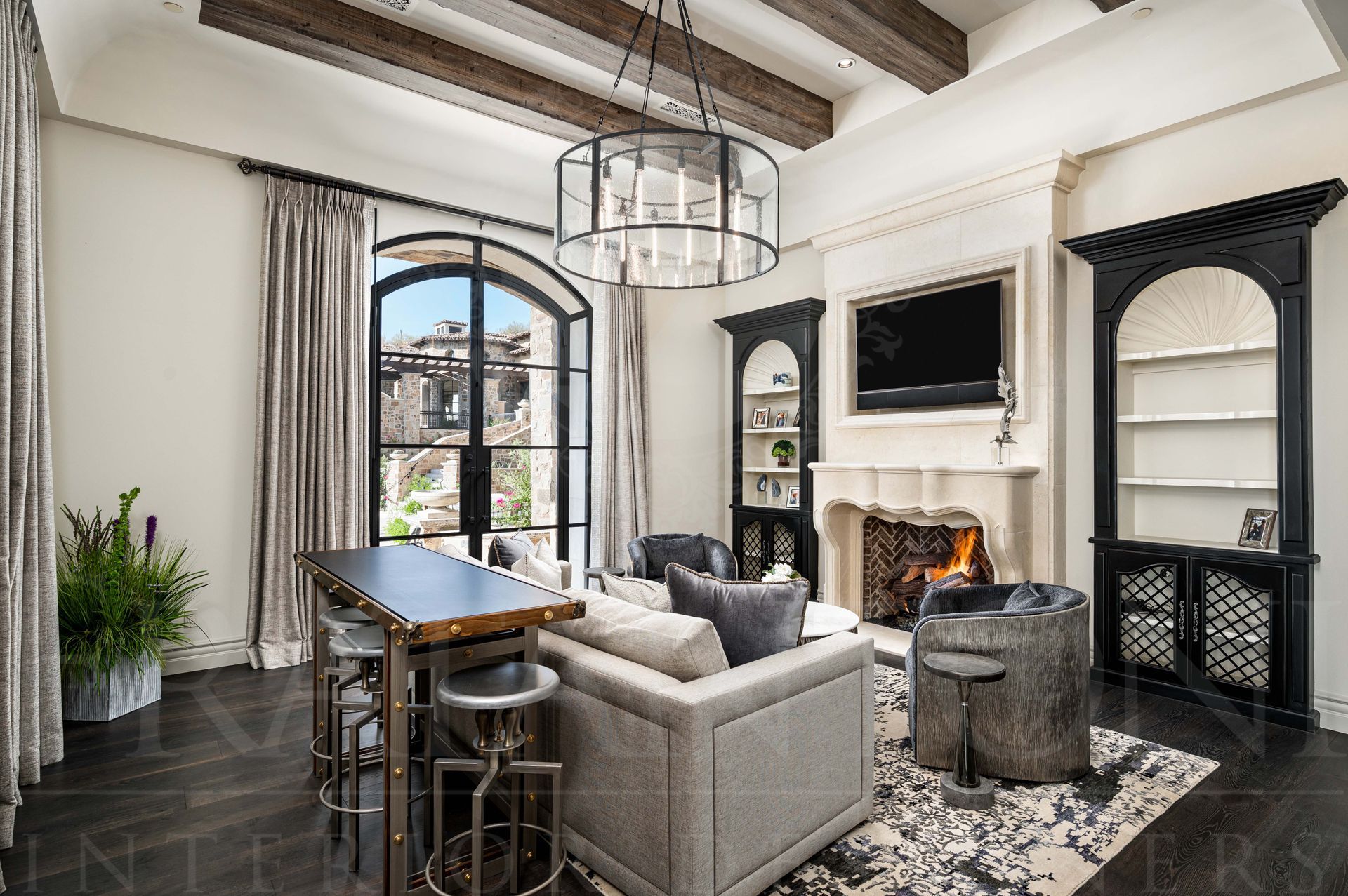 Bright guest house living room with marble fireplace, arched windows, gray sofa, built-in tv and black built-in shelves