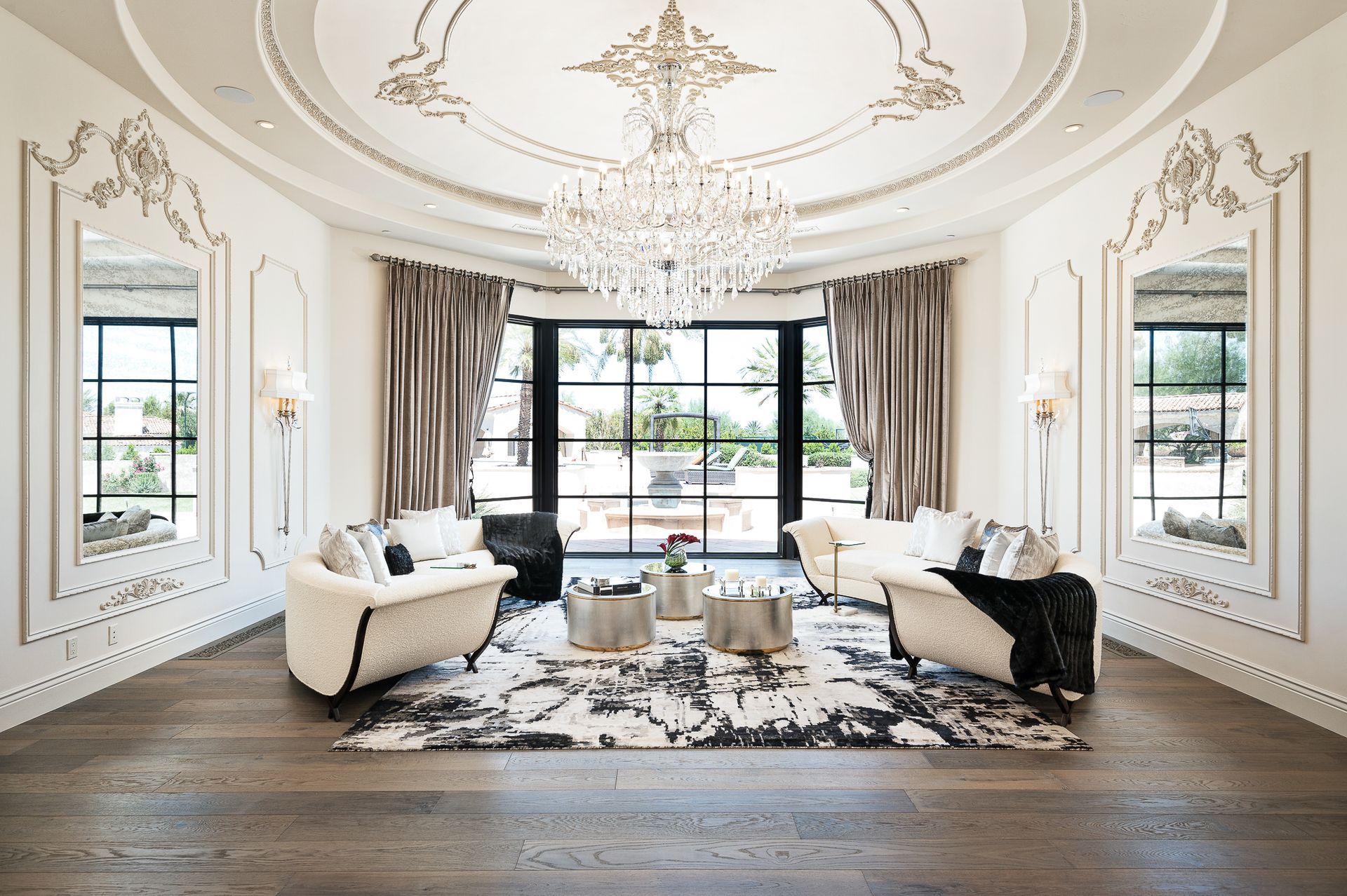 Elegant living room with a chandelier, two sofas, and a large window overlooking a patio.