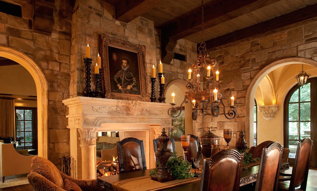 Elegant dining room with stone walls, fireplace, chandelier, and a portrait.
