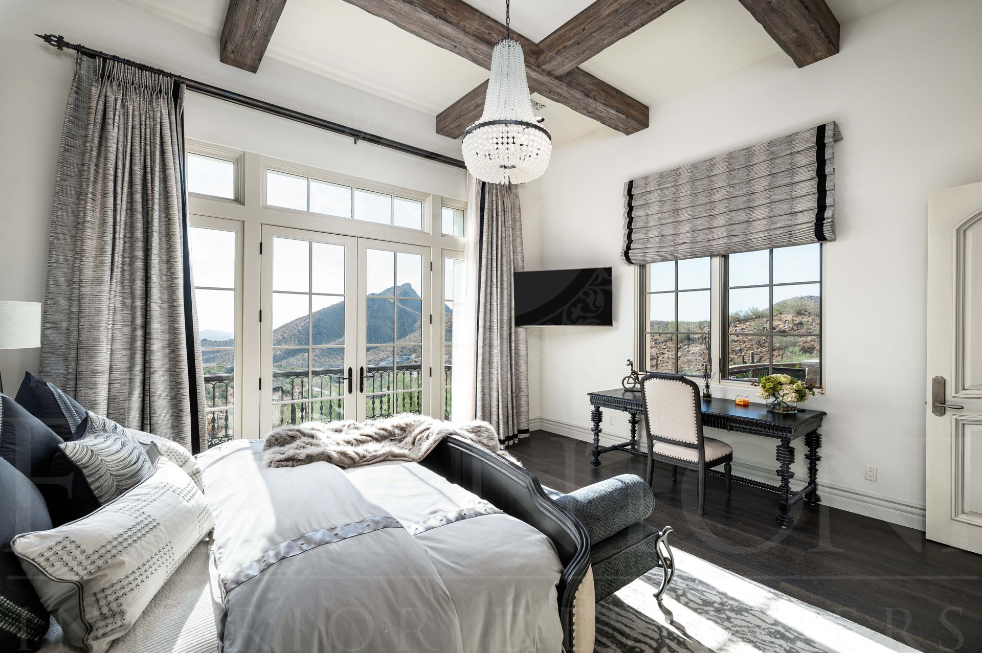 Bright custom bedroom with coffered beam ceiling, grey curtains, king bed, writing desk, and mountain-view windows designed by Fratantoni Interior Designers and located in Silverleaf