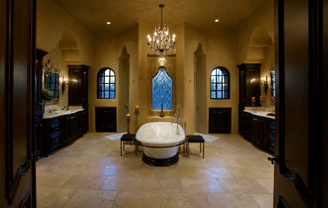 Luxurious bathroom with a chandelier, bathtub, and dark wood cabinetry.