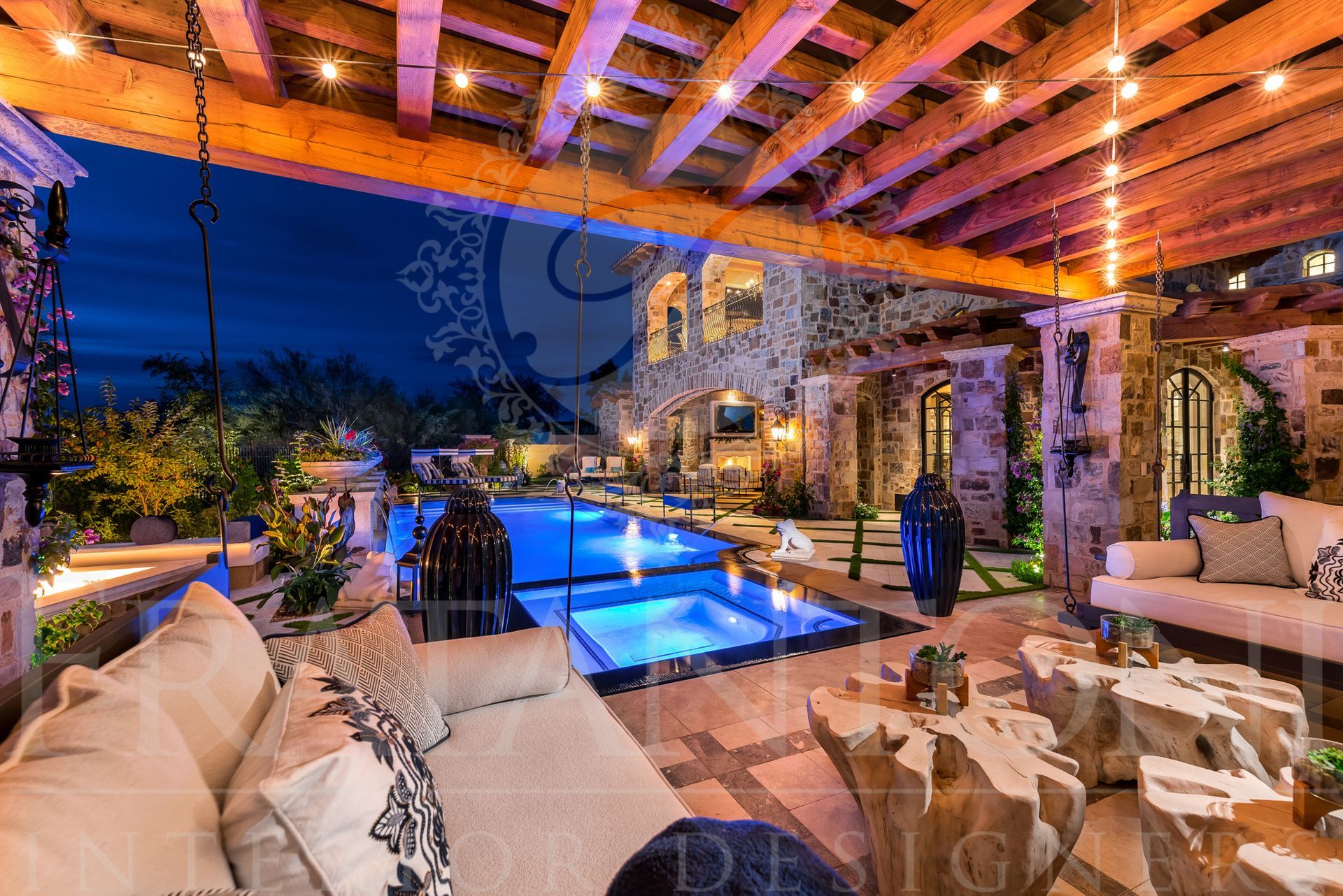 Night view of a luxurious outdoor patio with a resort-style pool, seating, and string lights with desert landscaping in scottsdale arizona.
