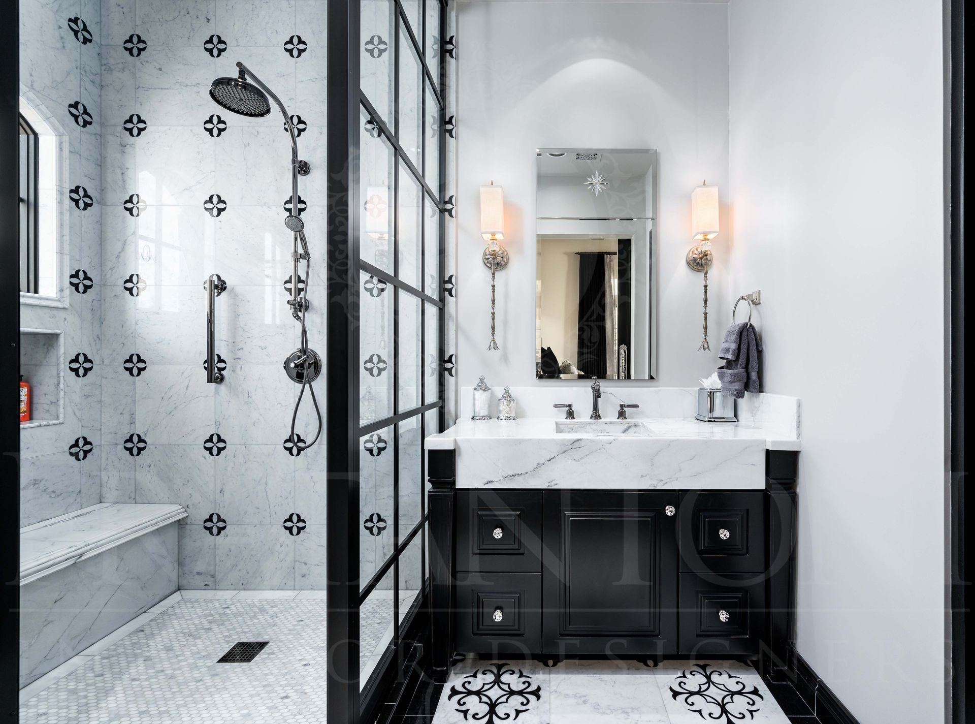 Modern black-and-white bathroom with glass shower, patterned shower tiles, a shower bench, dark vanity, marble counter tops, and wall sconces designed by Fratantoni Interior Designers in arizona