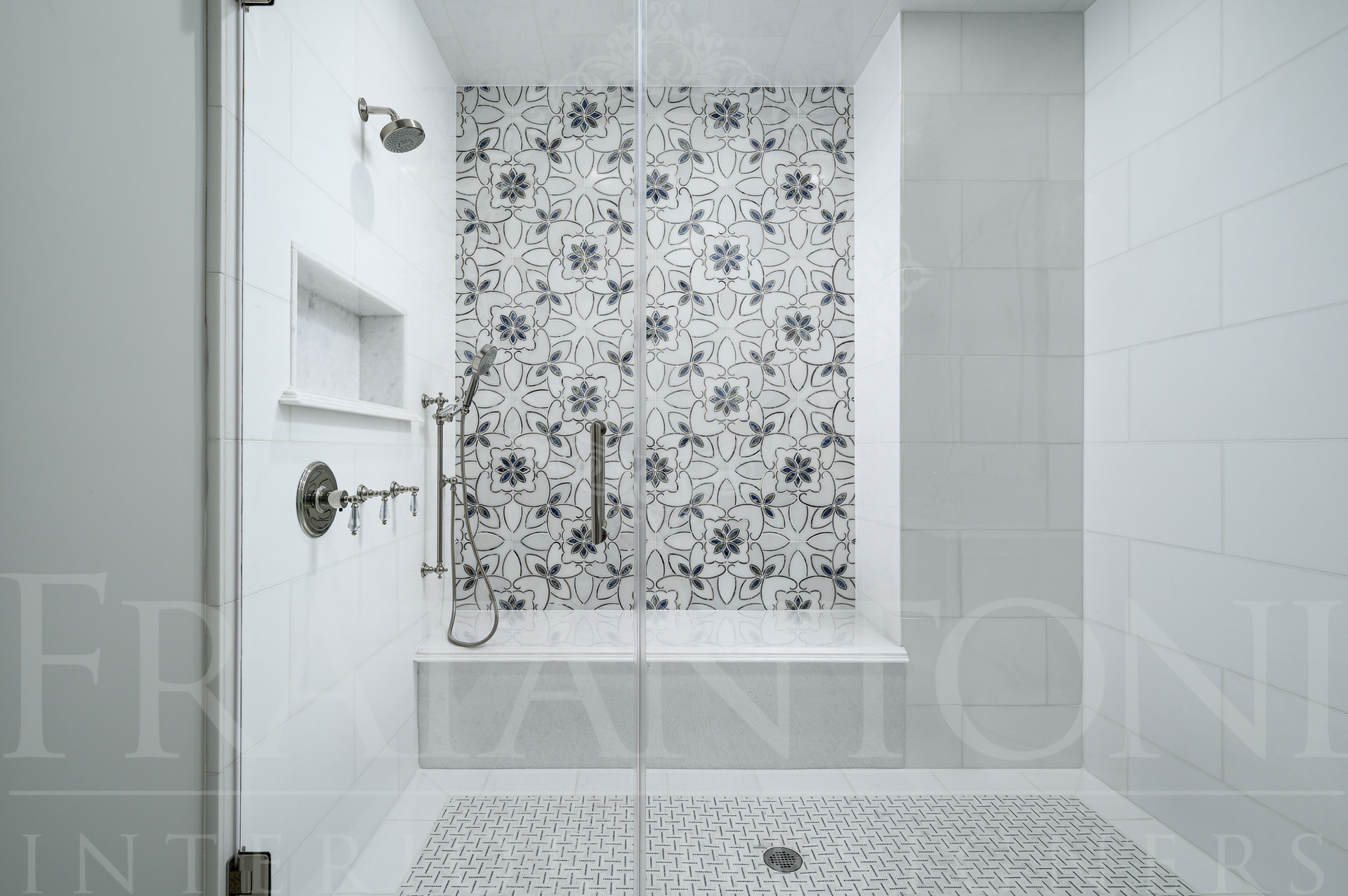Modern luxury marble bathroom with a floral-tiled shower, a shower bench, a shower niche, brass accents, white walls, and built-in shelves by fratantoni interior designers