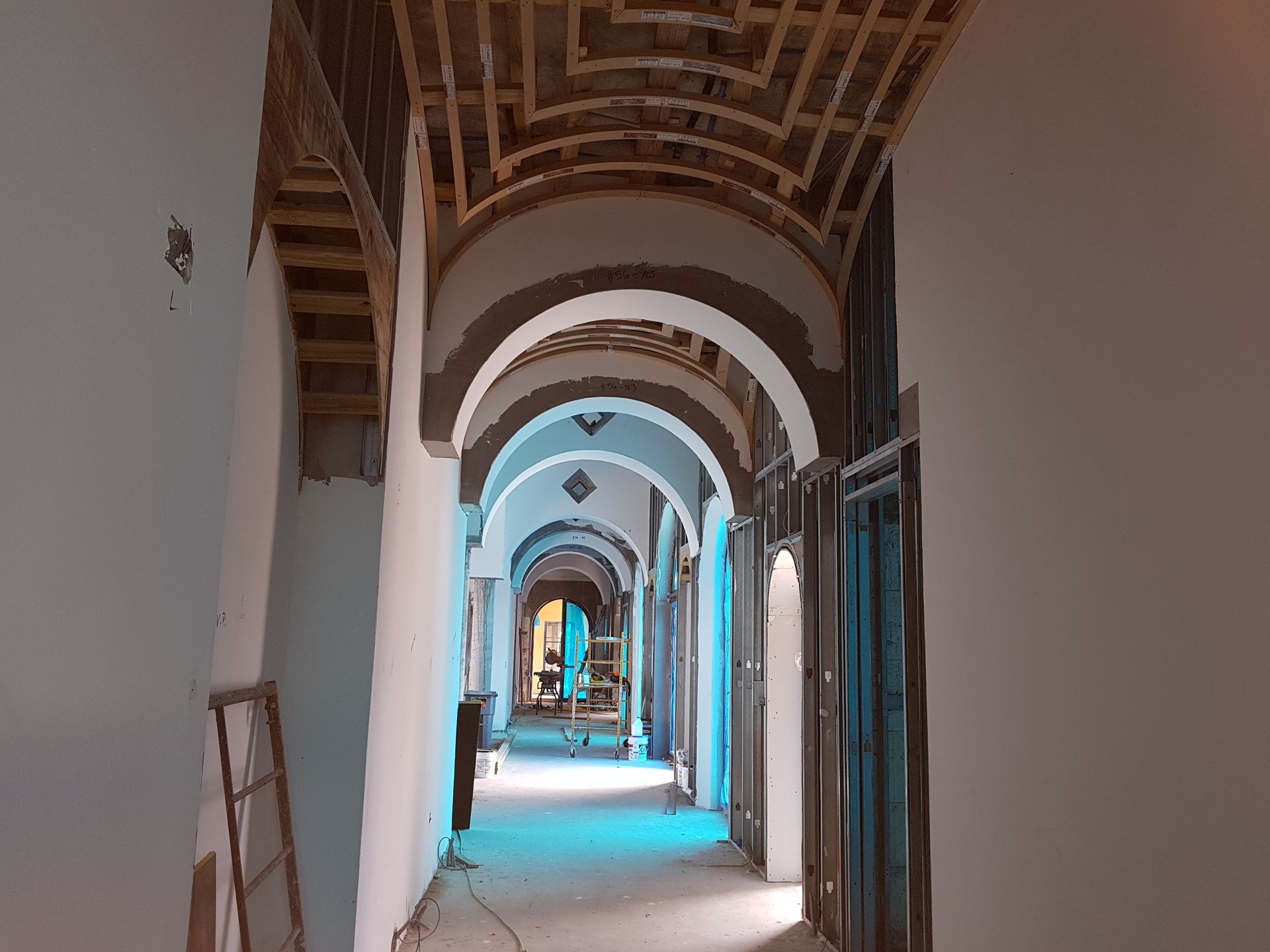 Long hallway under renovation, with arched ceilings and wooden supports.