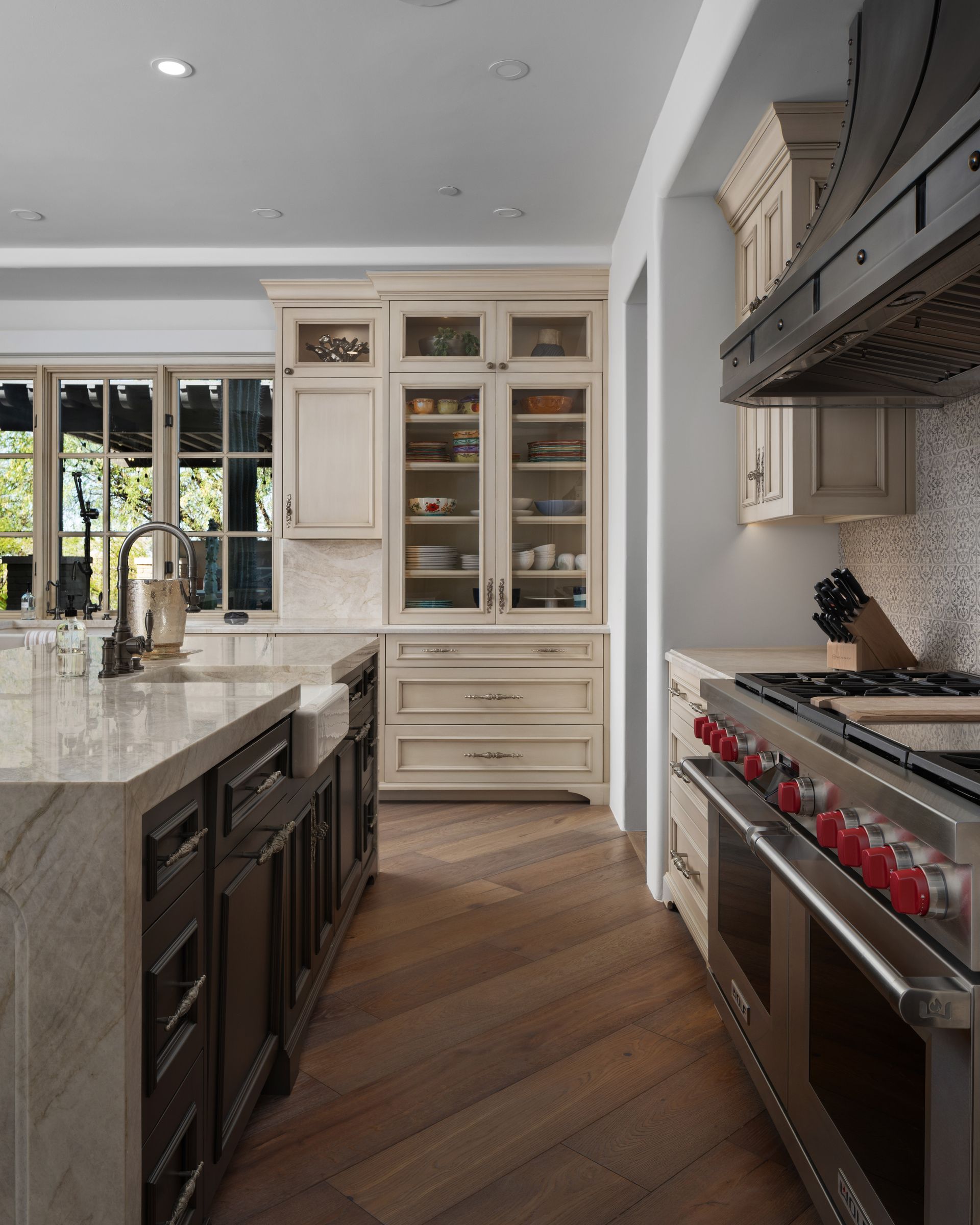 Elegant kitchen with dark cabinets, light countertops, and wood floors. Stainless steel appliances.