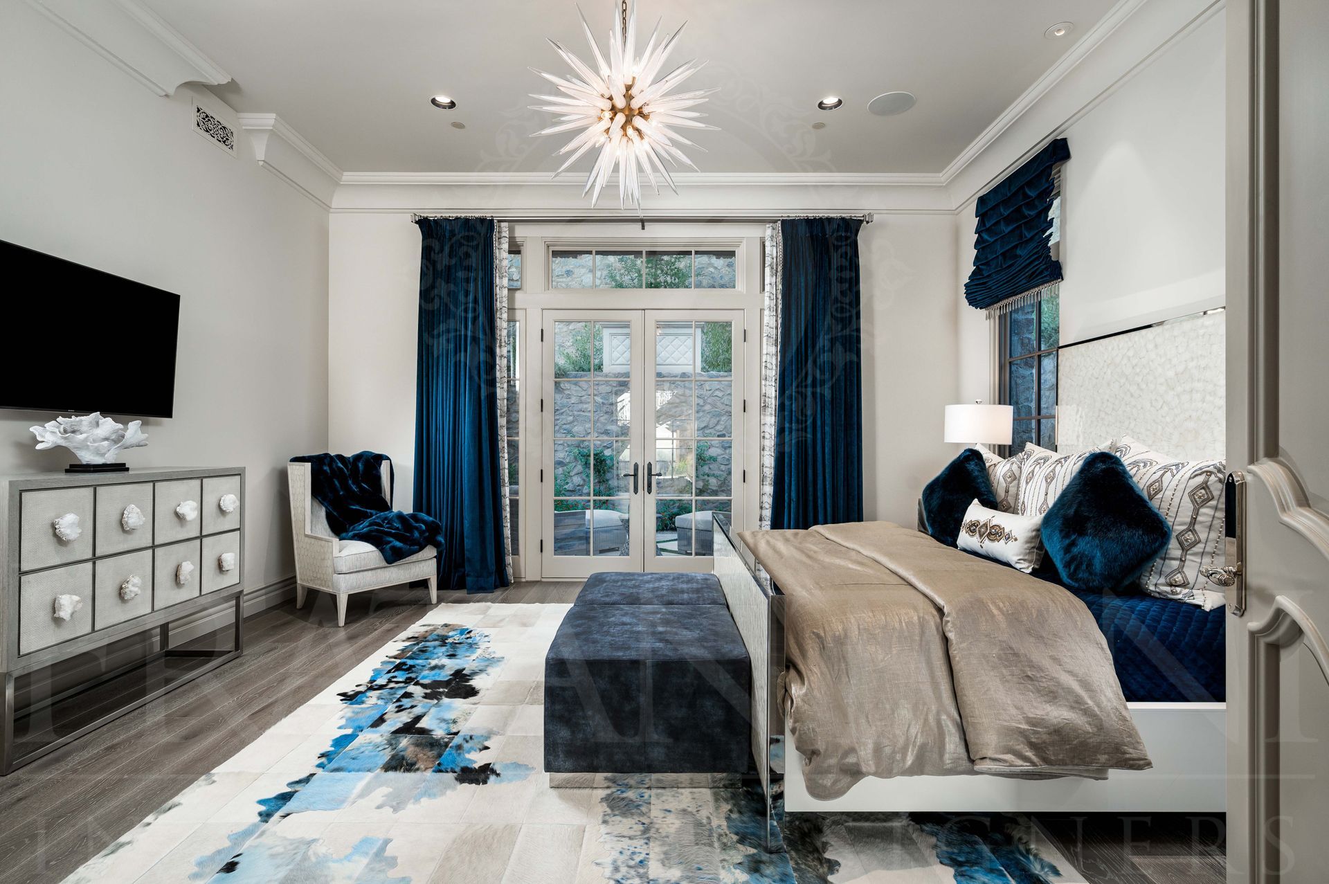 Luxury custom blue-and-white bedroom with a king sized bed, chaise, rug, dresser, and French doors to a balcony designed by Fratantoni Interior Designers in scottsdale, arizona