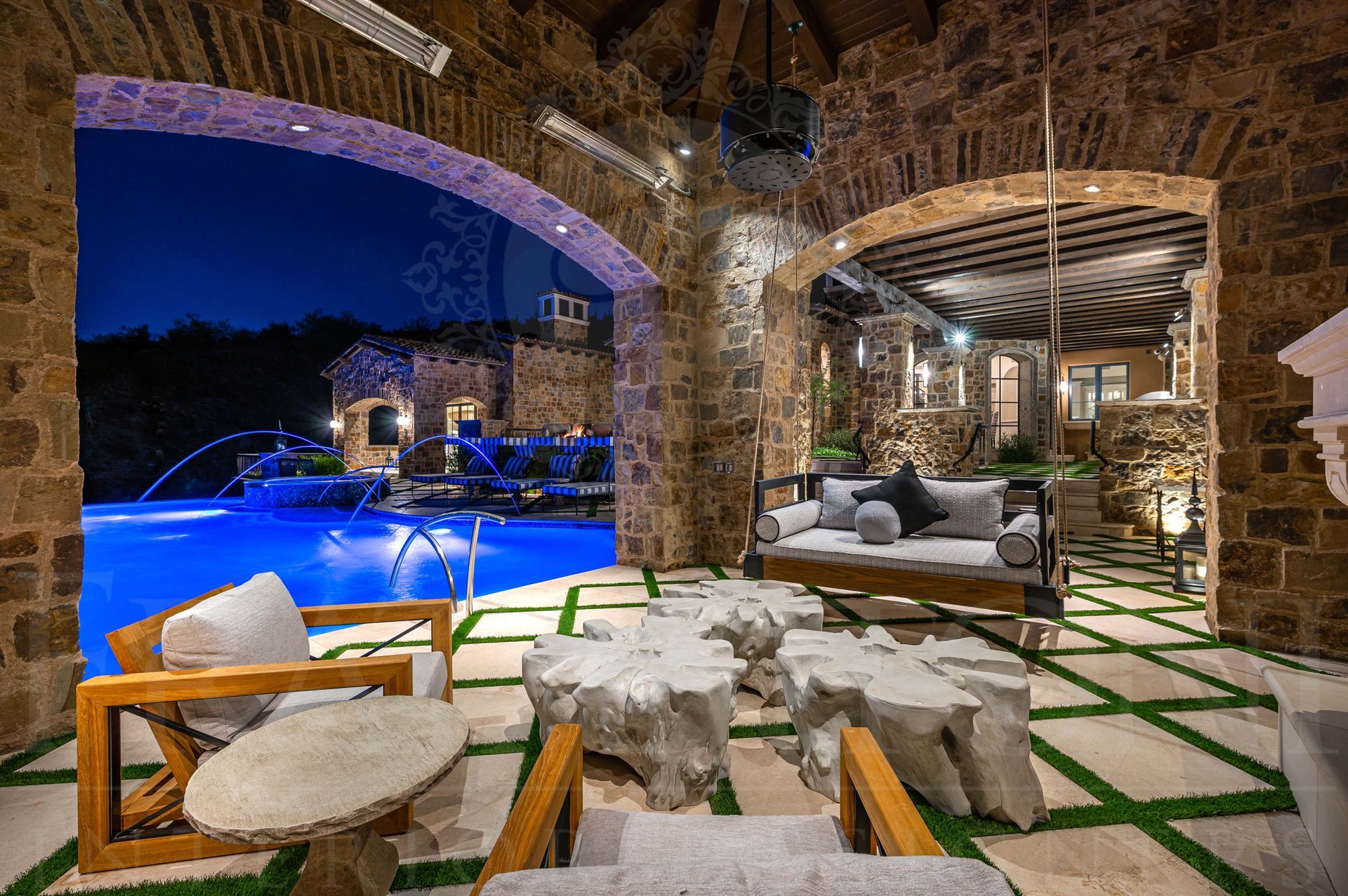 Luxury French patio design with resort-style pool, hanging sofa, and stone arches