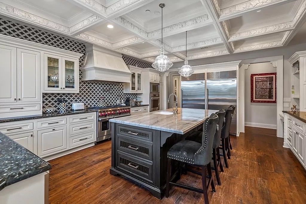 A large kitchen with a large island in the middle and stainless steel appliances.