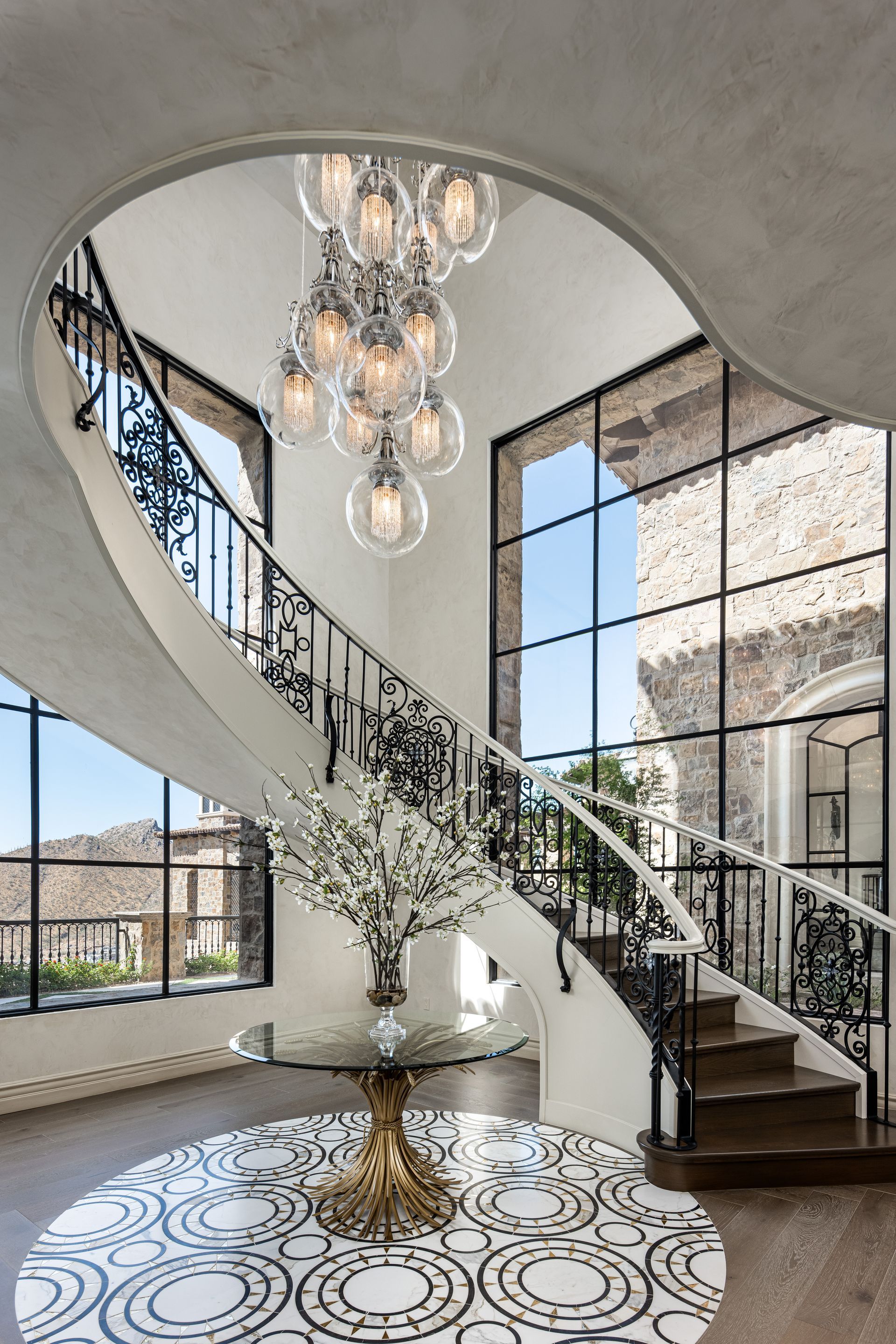 A spiral staircase in a house with a chandelier hanging from the ceiling.