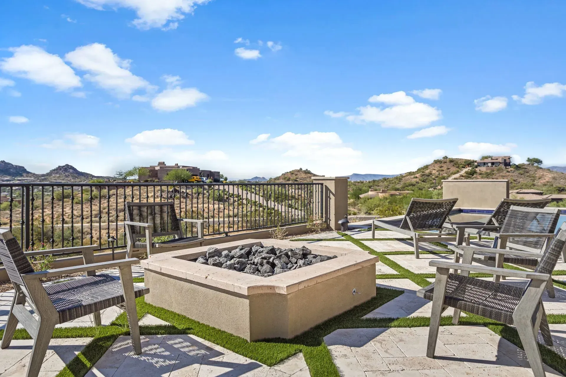 Patio with fire pit, seating, and scenic mountain views under a blue sky.