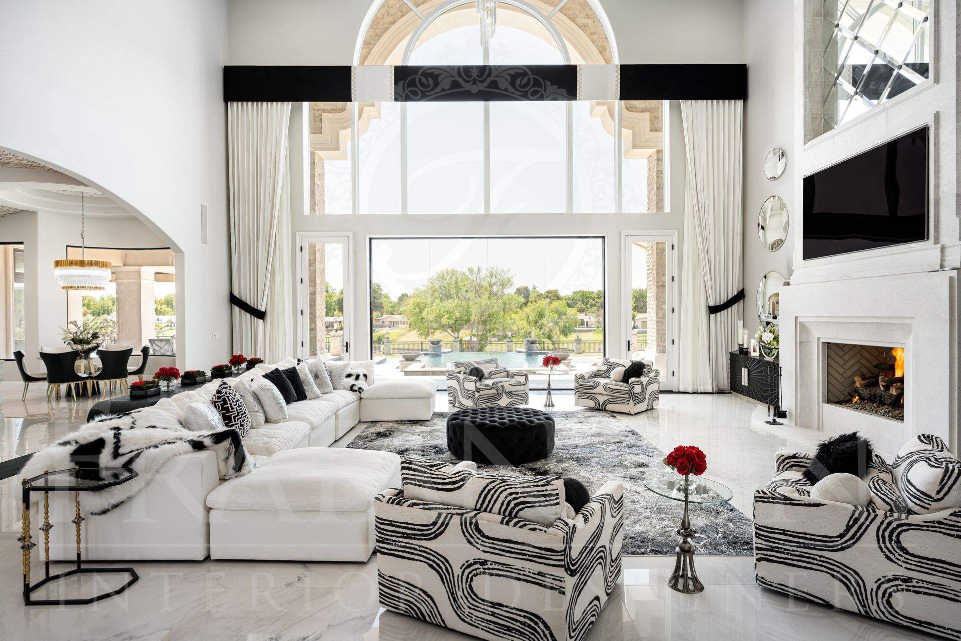 Luxurious living room with white marble floors, large windows, and black and white patterned furniture.