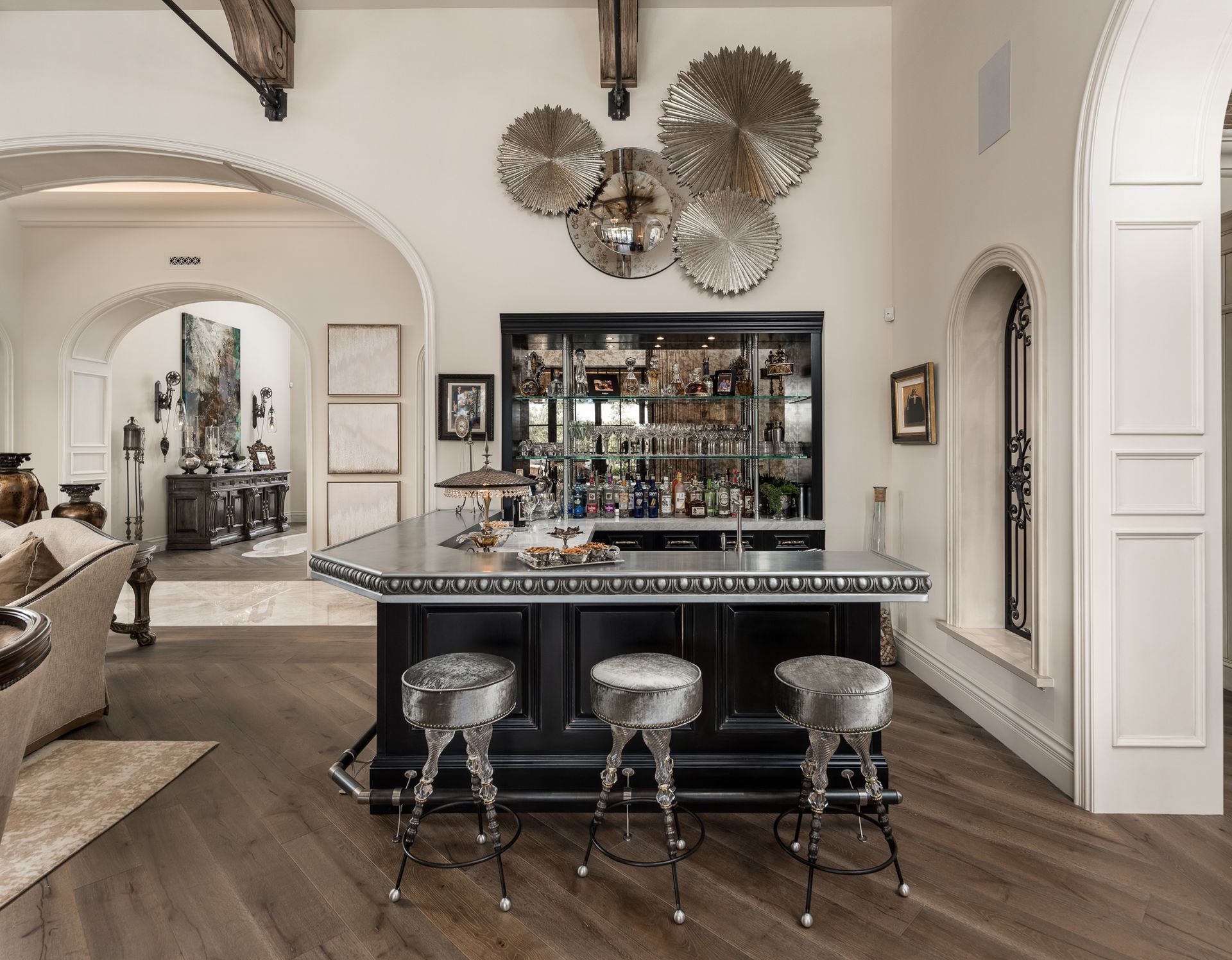 Bar area with chrome stools, dark cabinets, and metal art on the wall.