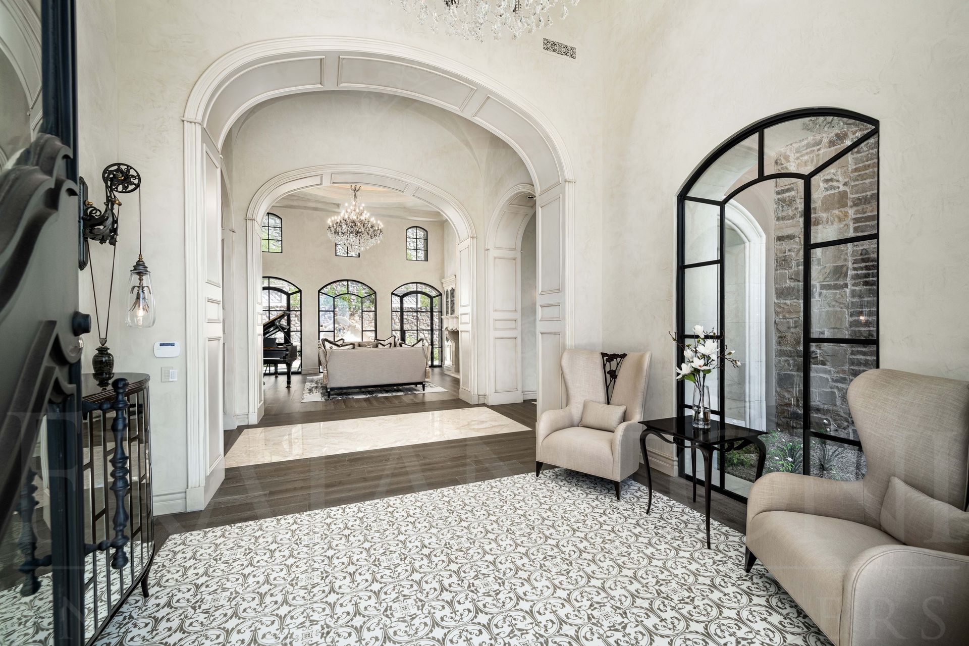 French style entry interior design with paneled arches, arched windows, and custom mosaic floors