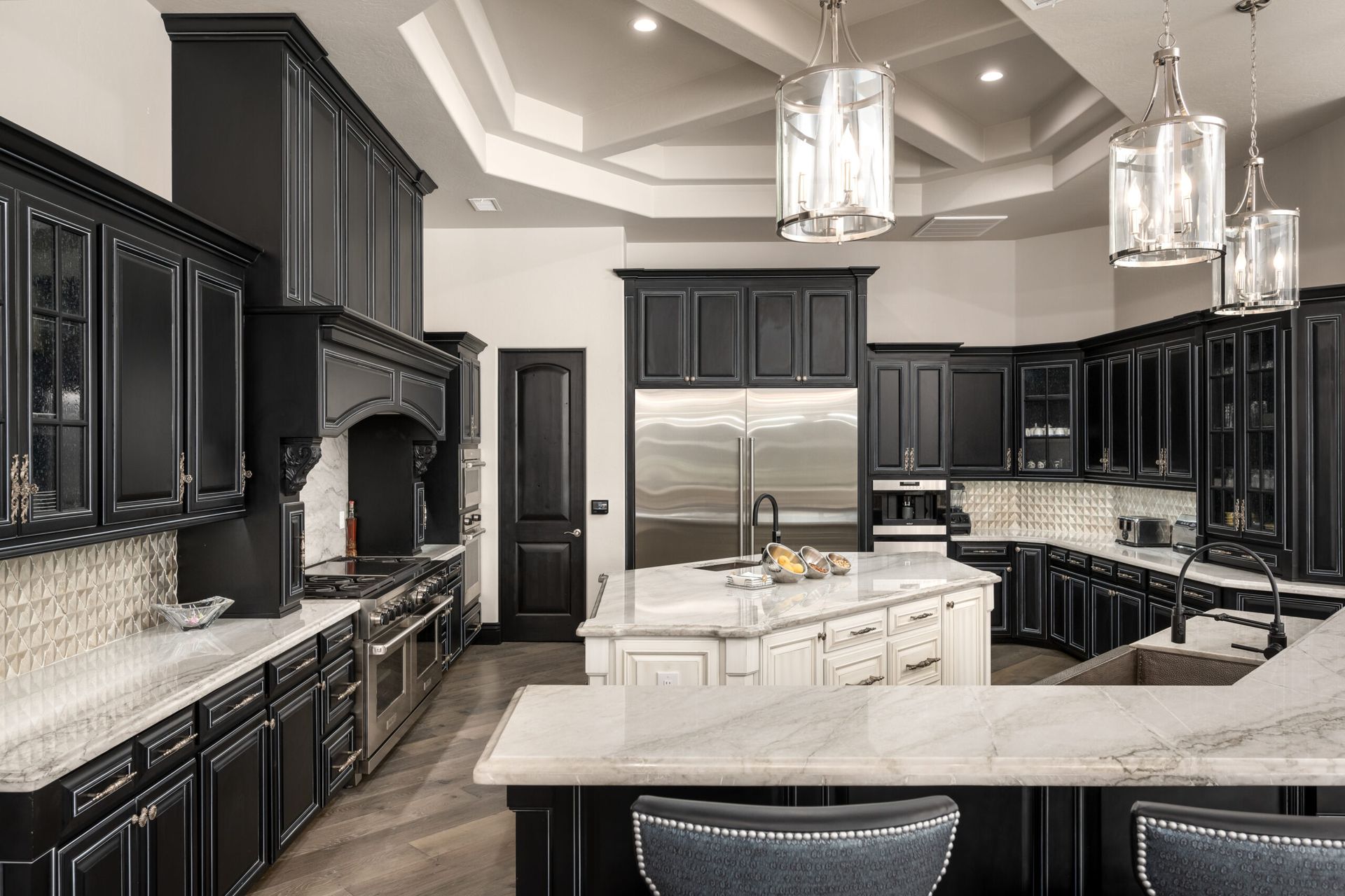 A kitchen with black cabinets , white counter tops , stainless steel appliances and a large island.