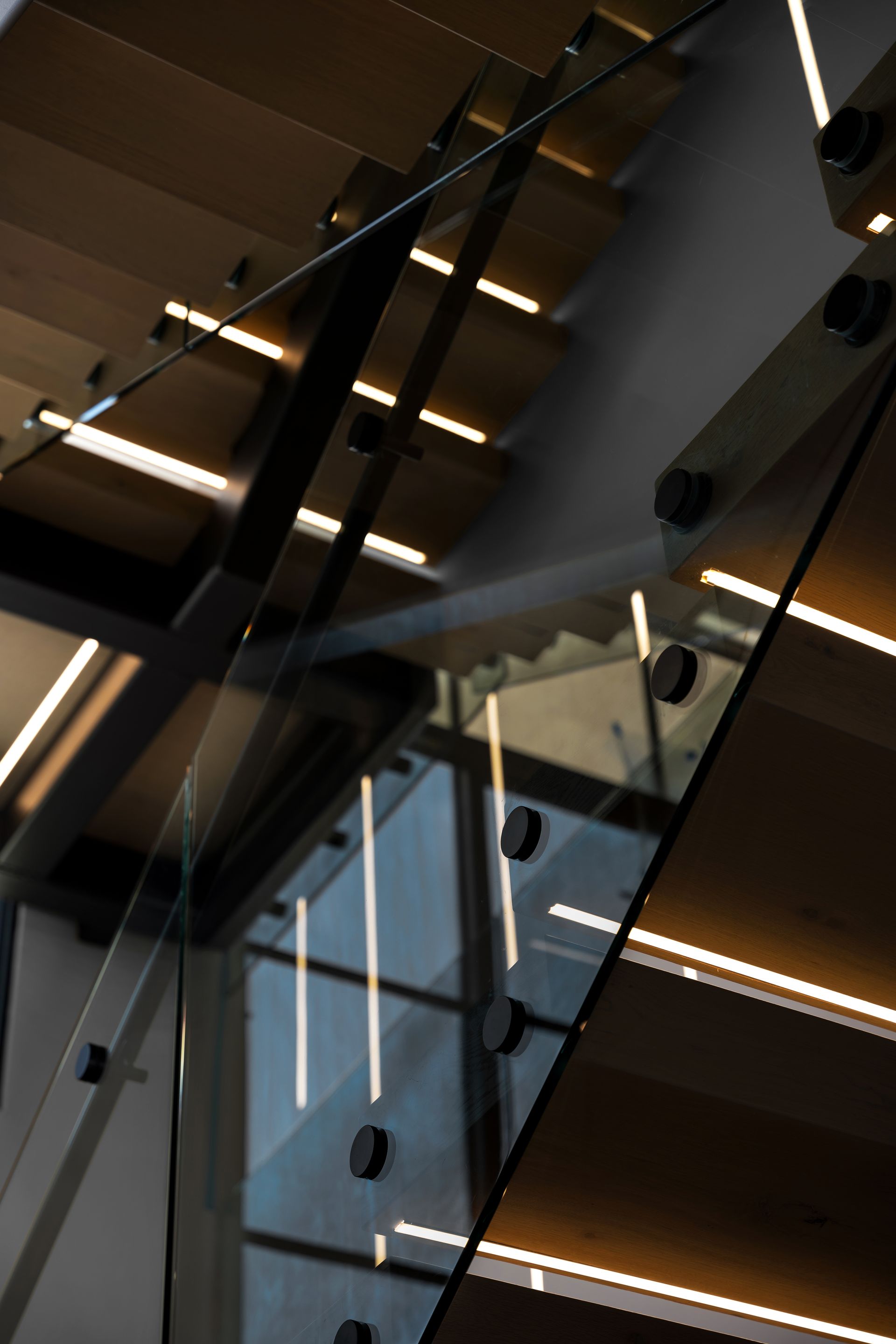 Wooden staircase with glass panels and built-in lighting.
