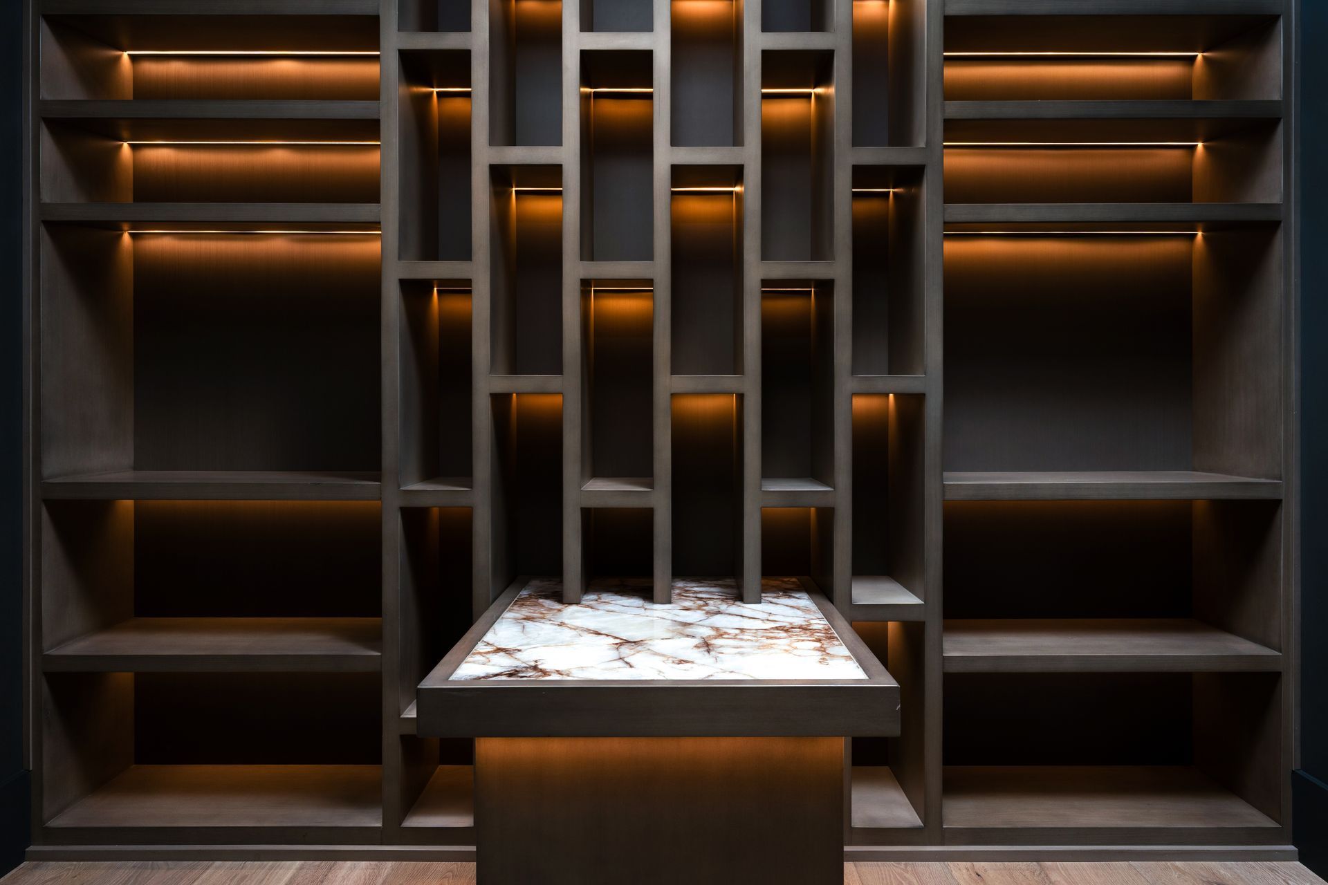 Dark wooden shelving unit with built-in lights and a central raised section filled with stones.